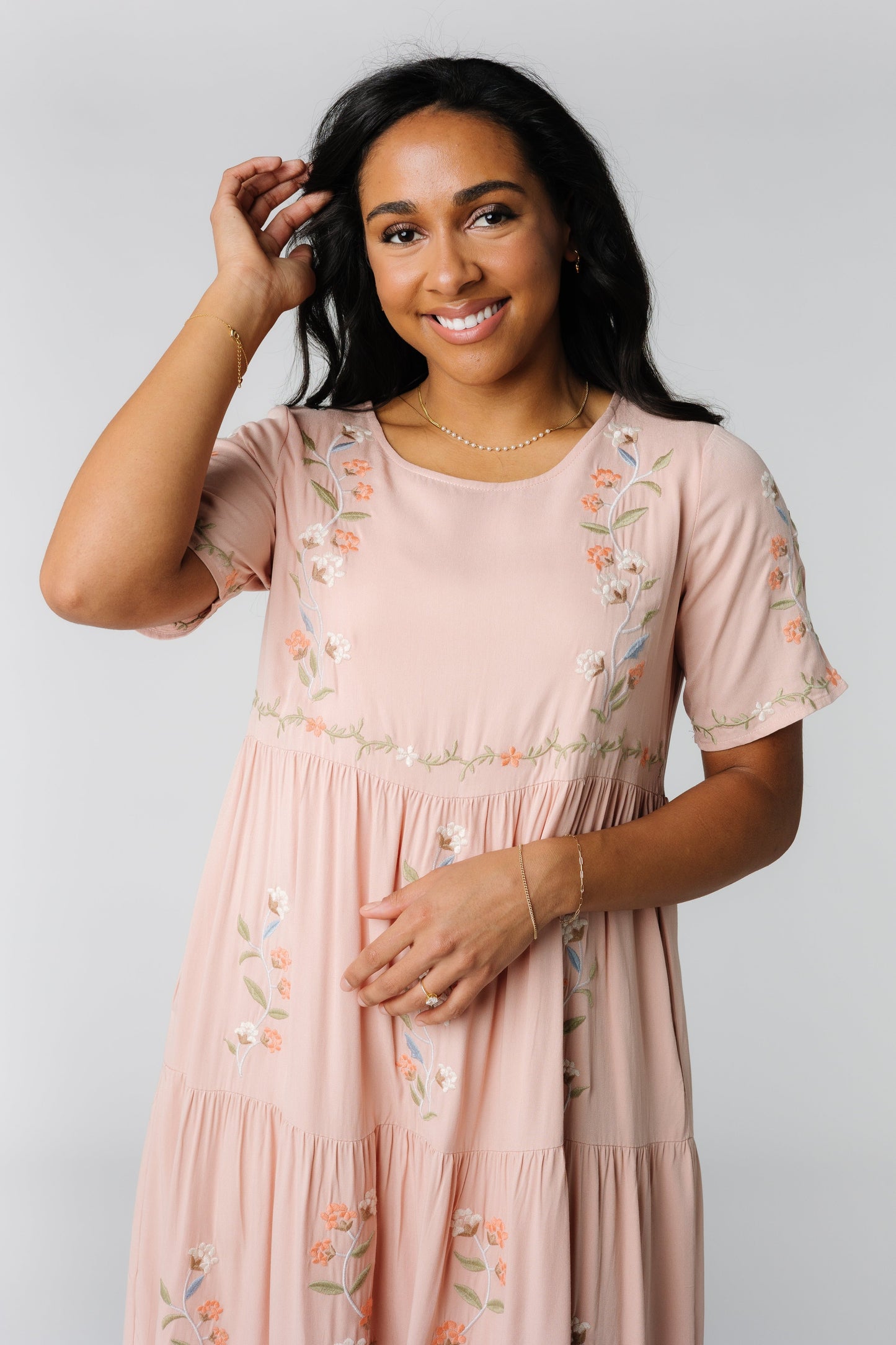 Close view of light pink embroidered tiered dress with slight scoop neckline