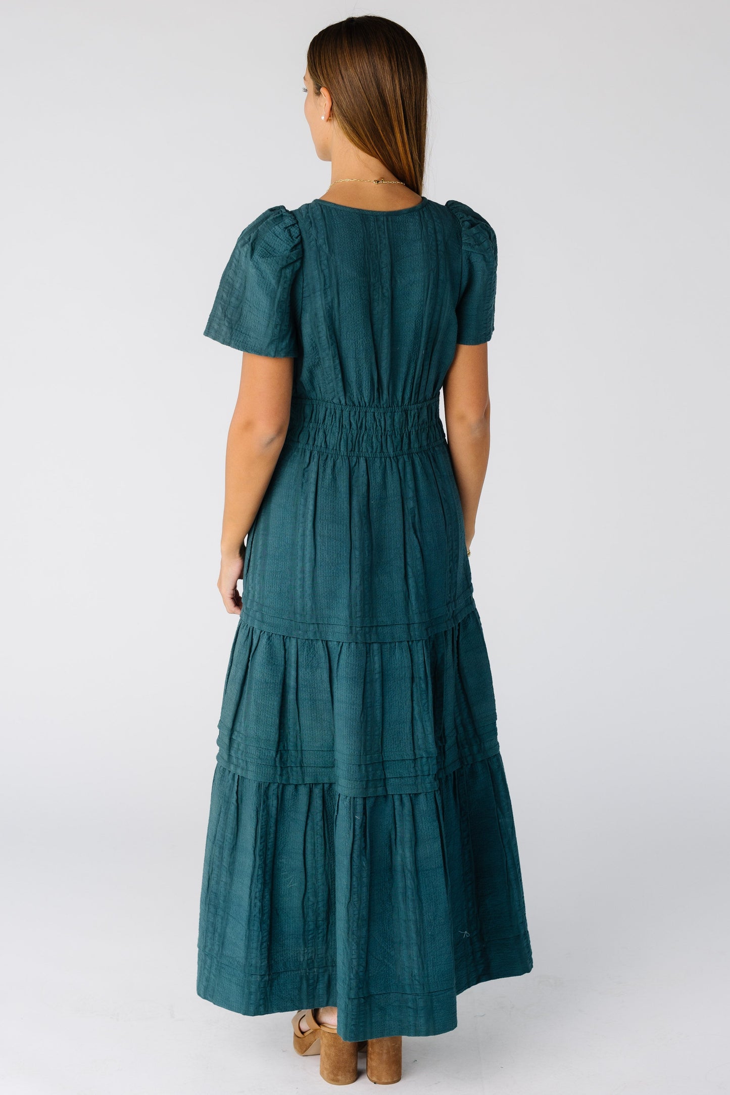 Back view of a woman wearing a teal maxi dress with short sleeves