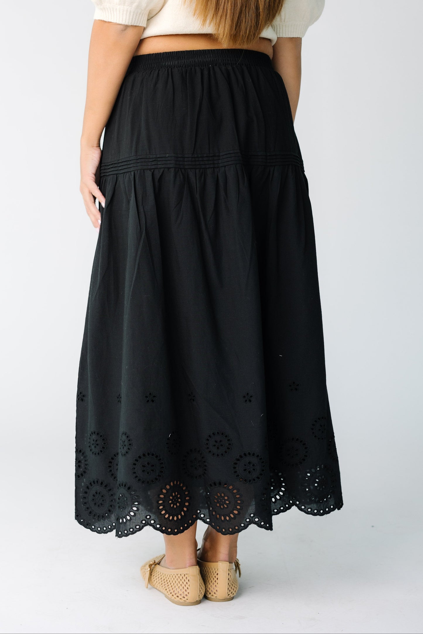 Back view of a woman wearing a black eyelet midi skirt