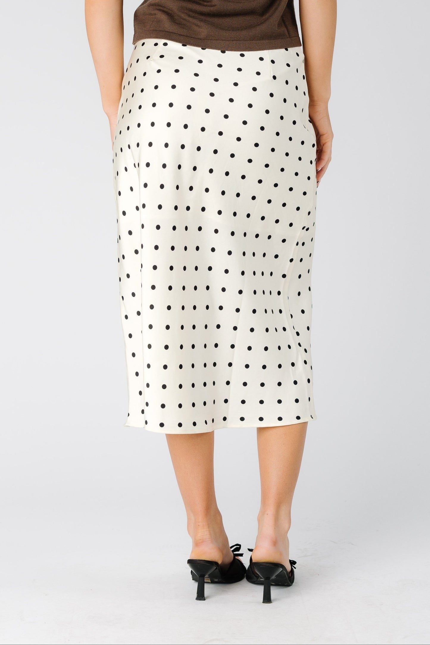 Back view of a woman wearing a cream polka dot midi skirt