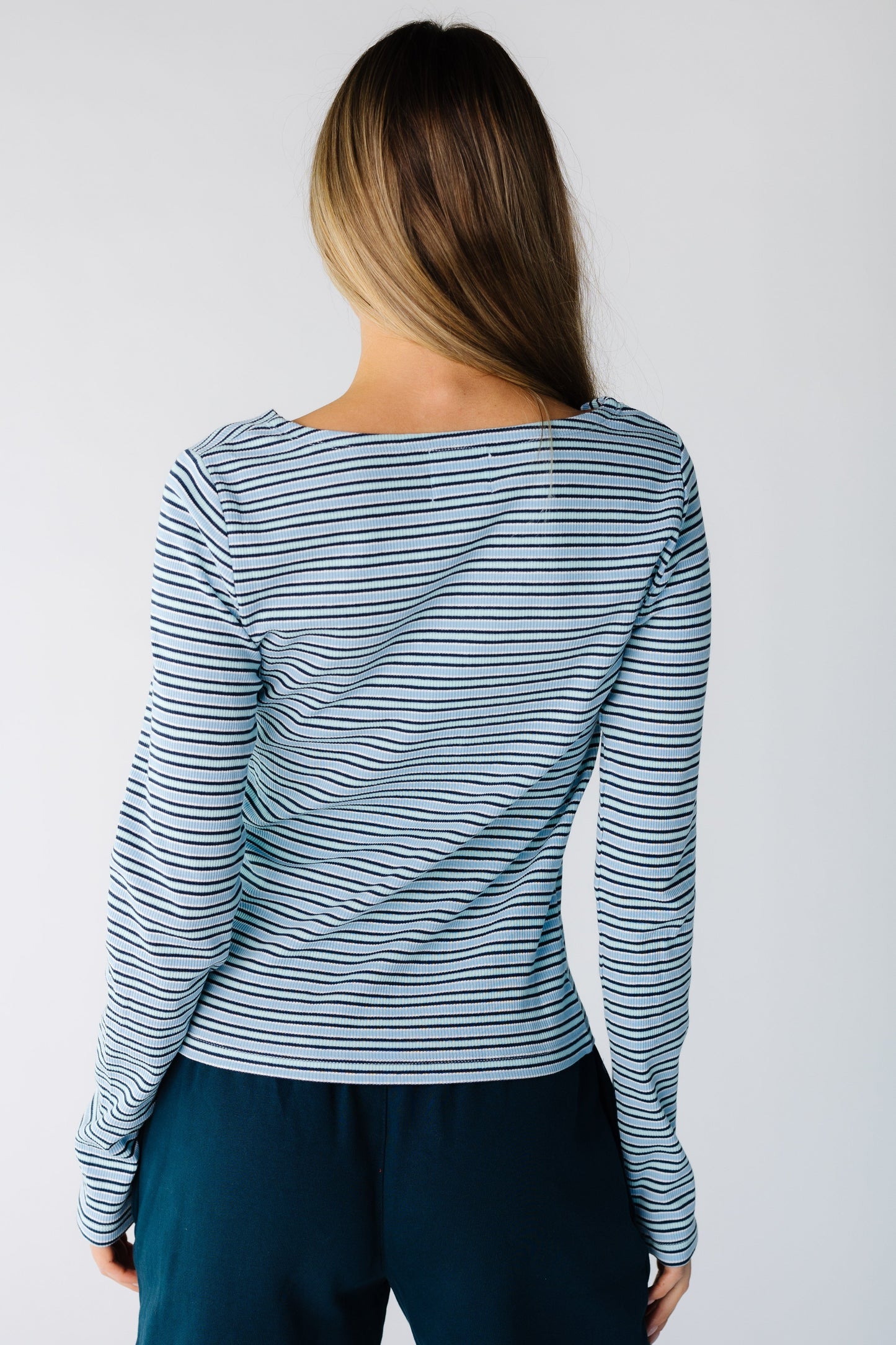 Back view of a woman wearing a light blue stripe long sleeve top