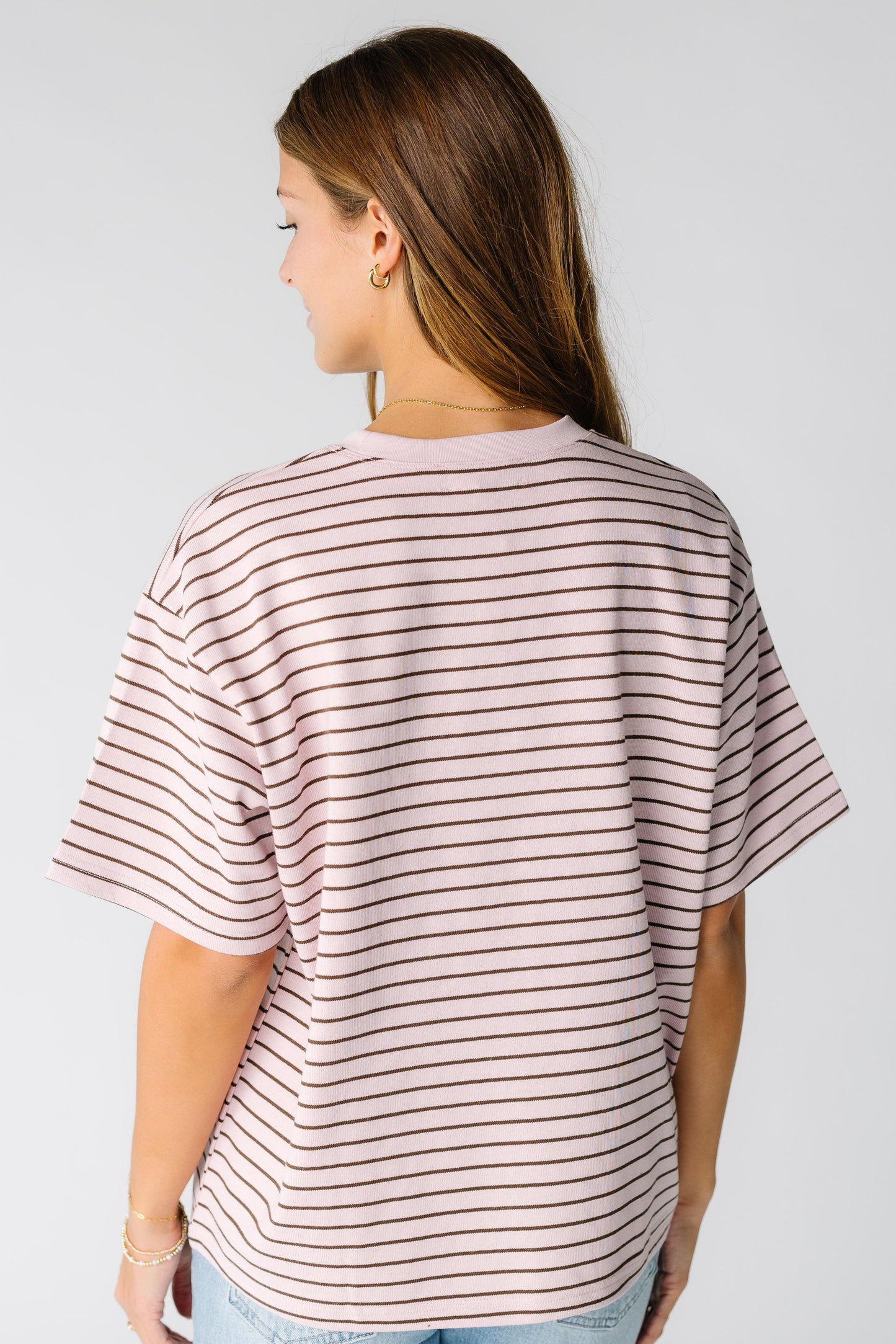 Back view of a woman wearing a pink stripe boxy tee with short sleeves