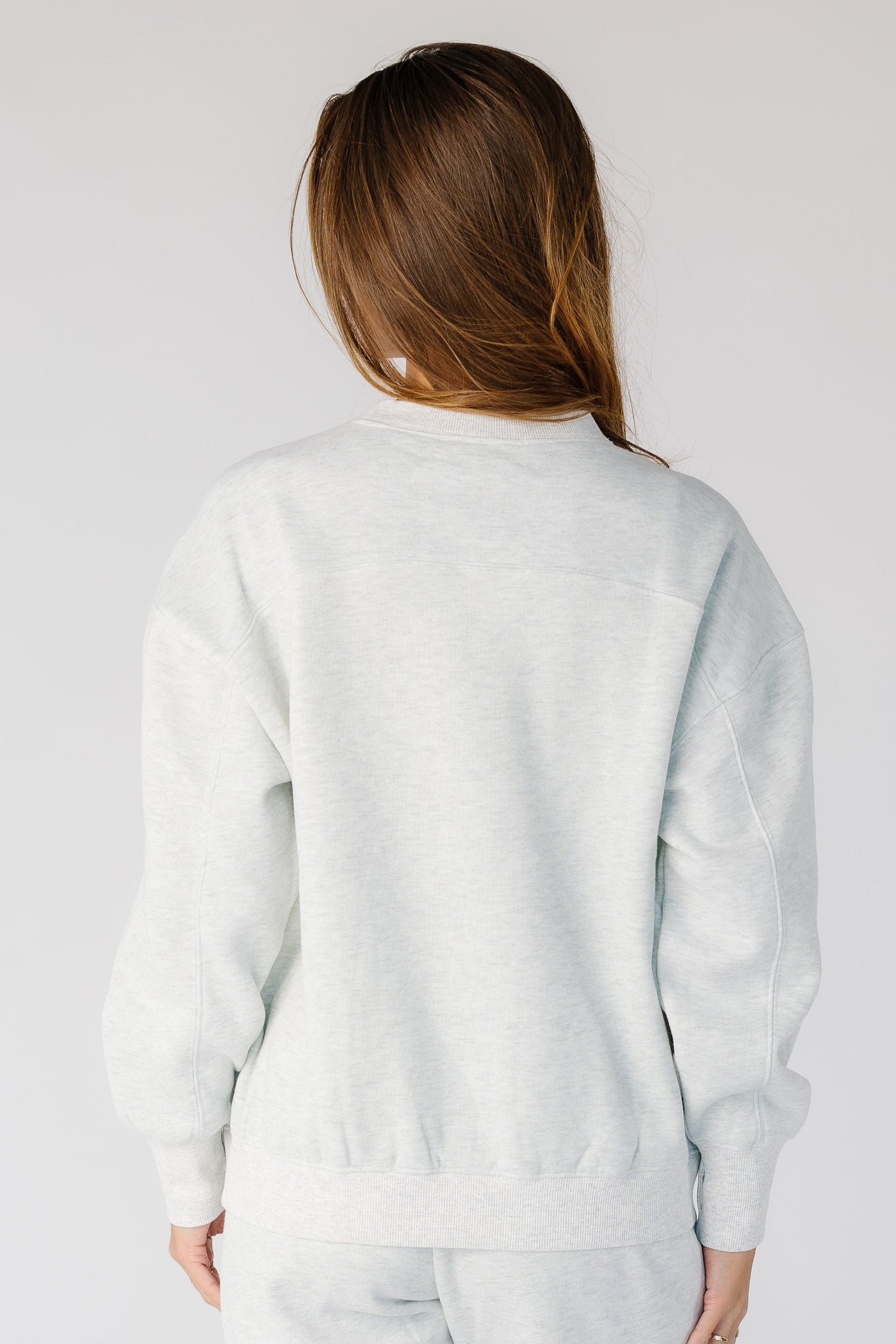 Back view of a woman wearing a light heather grey with long sleeves