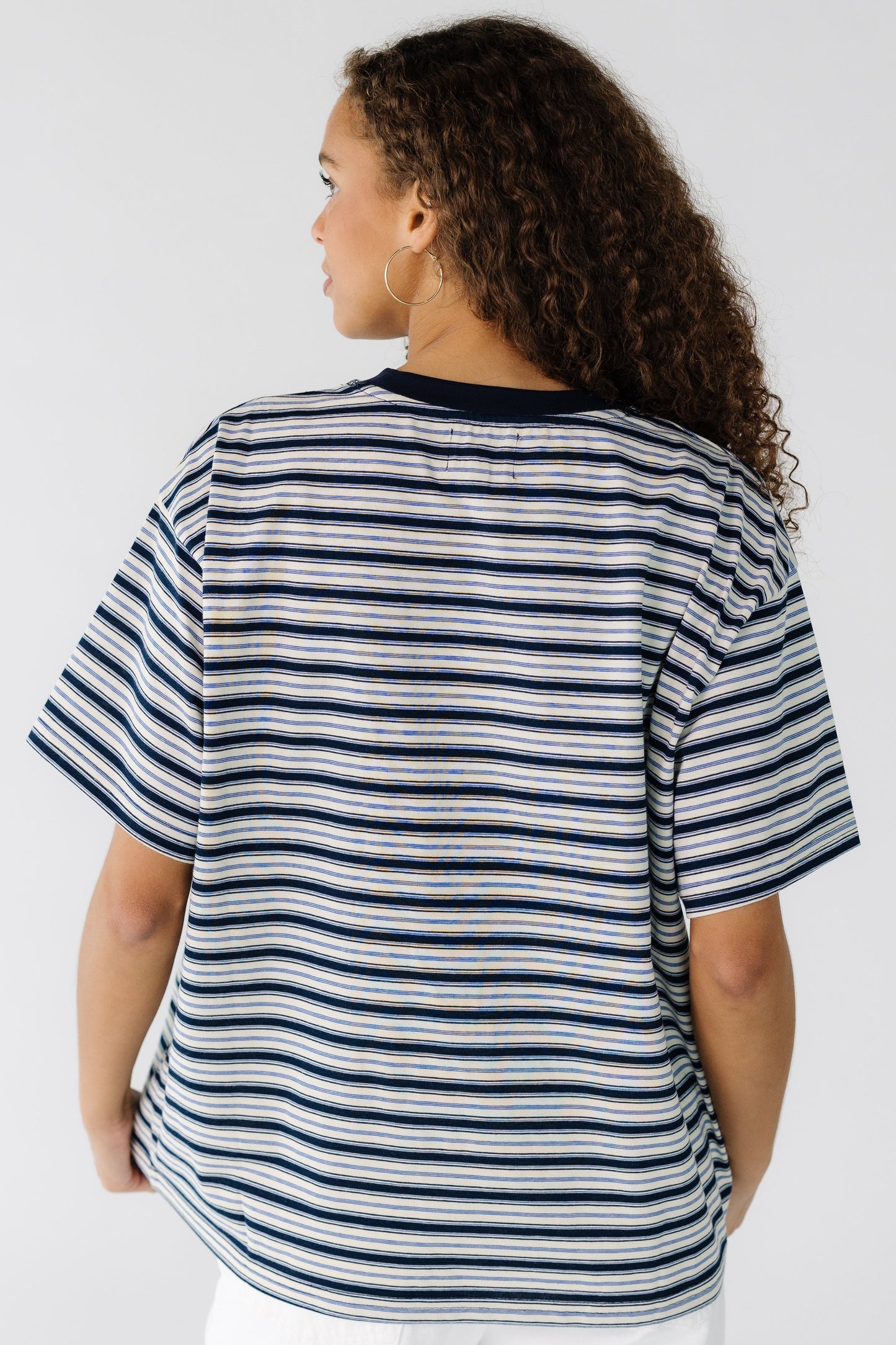 Back view of a teenage girl wearing an ivory and navy stripe short sleeve tee.