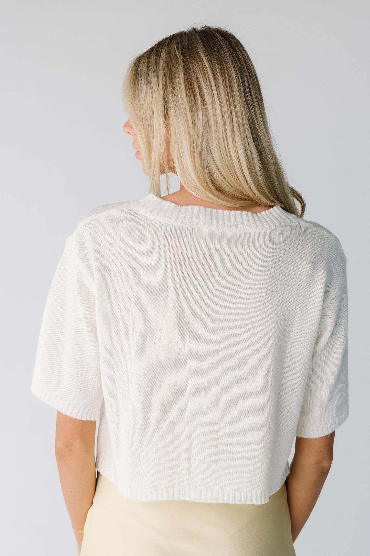 Back view of cream loose cardigan with half length sleeves