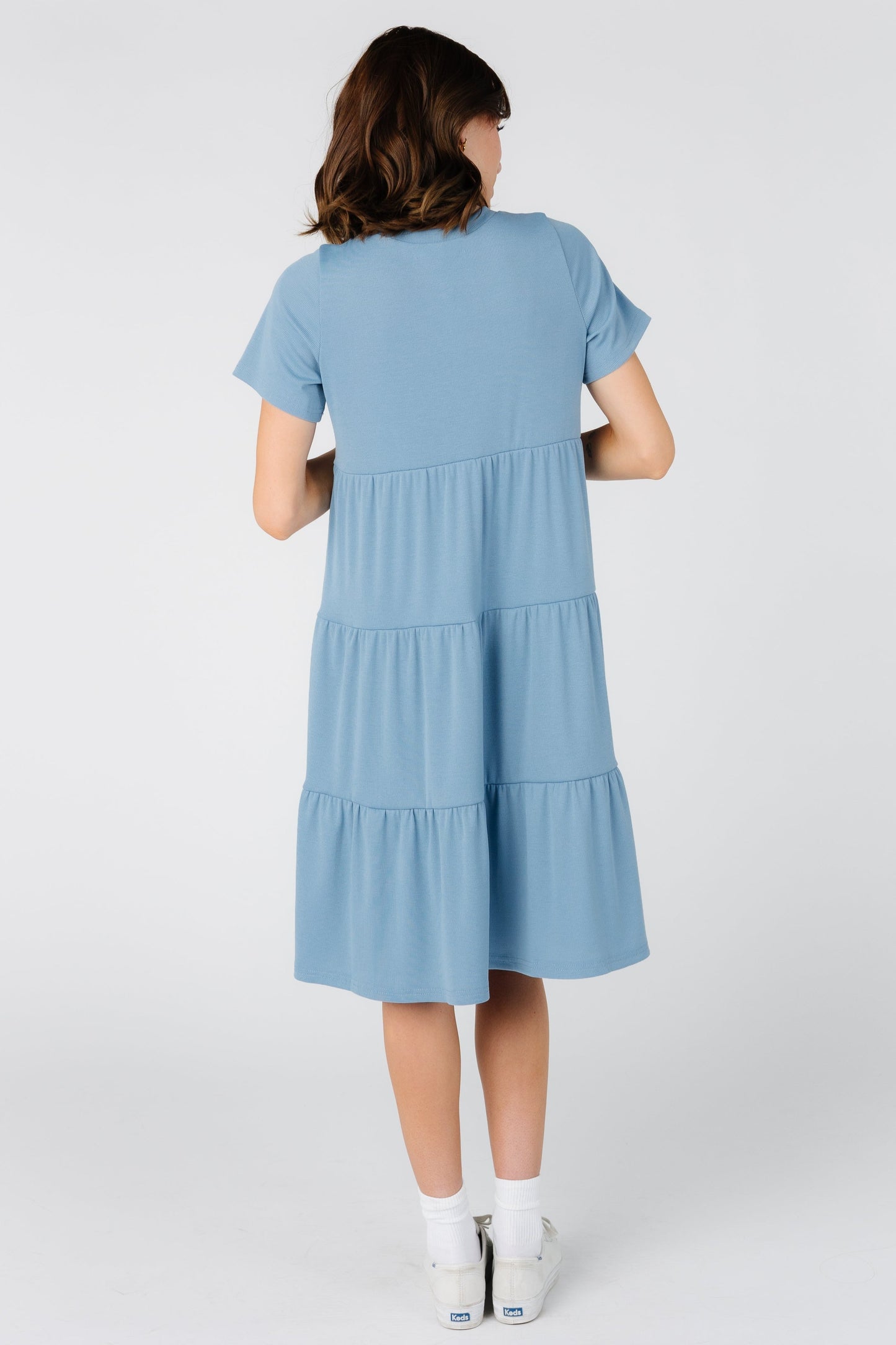 Back view of woman wearing a tiered knee length dress in blue