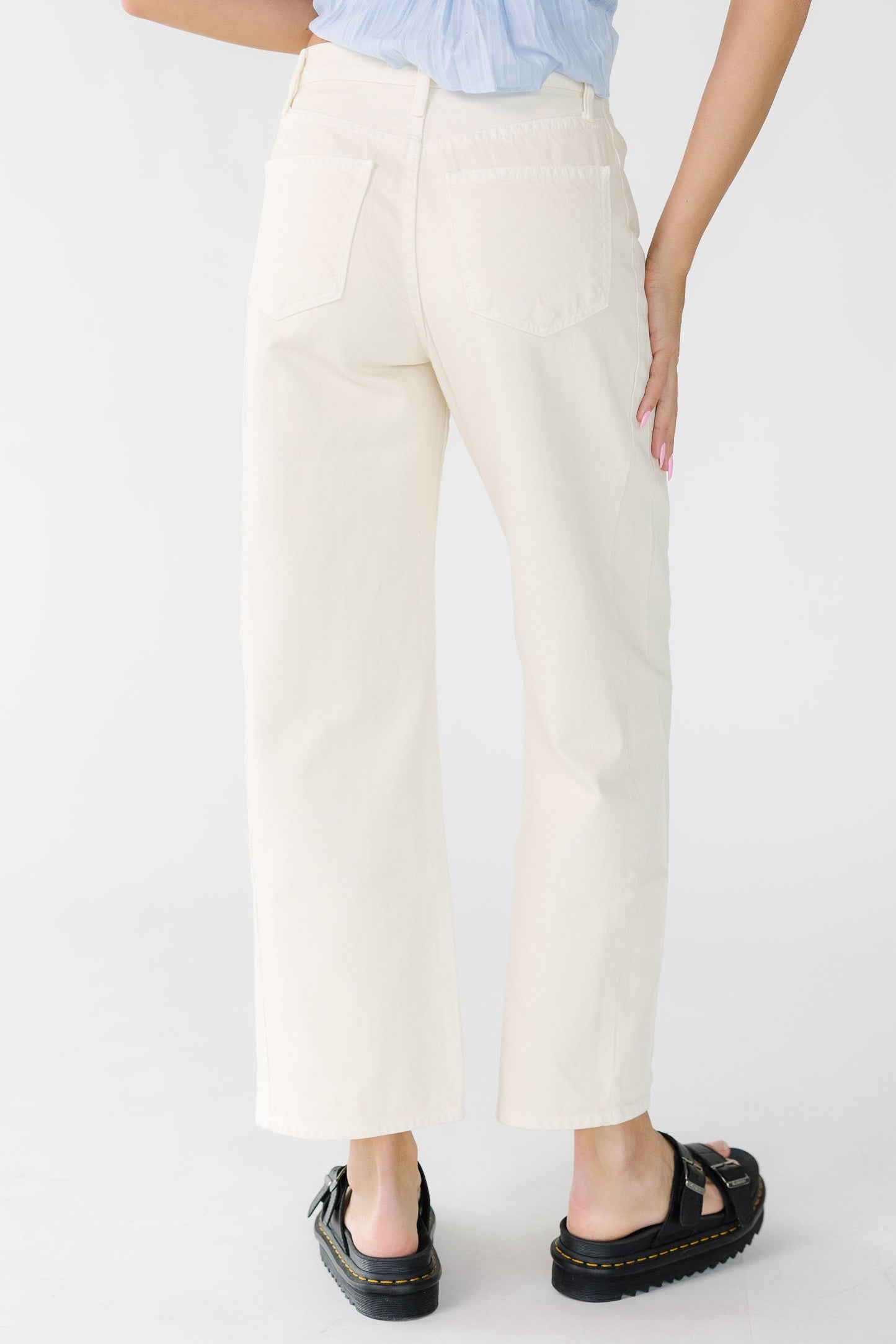 Back view of a woman wearing a pair of barrel jeans that are close fitting through the waist and hip with wide legs.