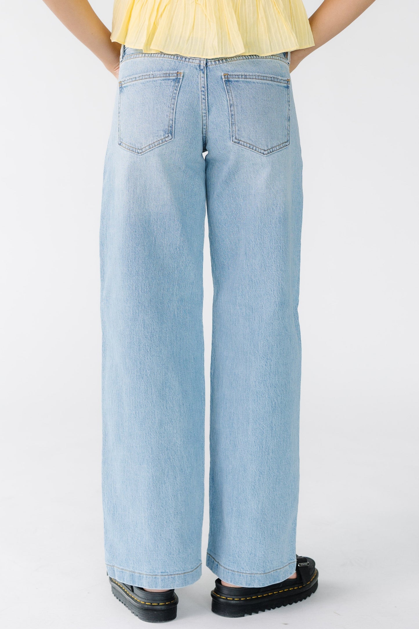 Back view of a woman wearing a pair of wide leg, loose fitting jeans.