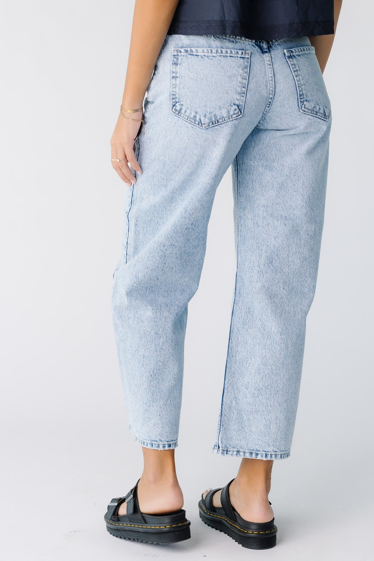 Back view of a young woman wearing wide leg barrel jeans in light denim.