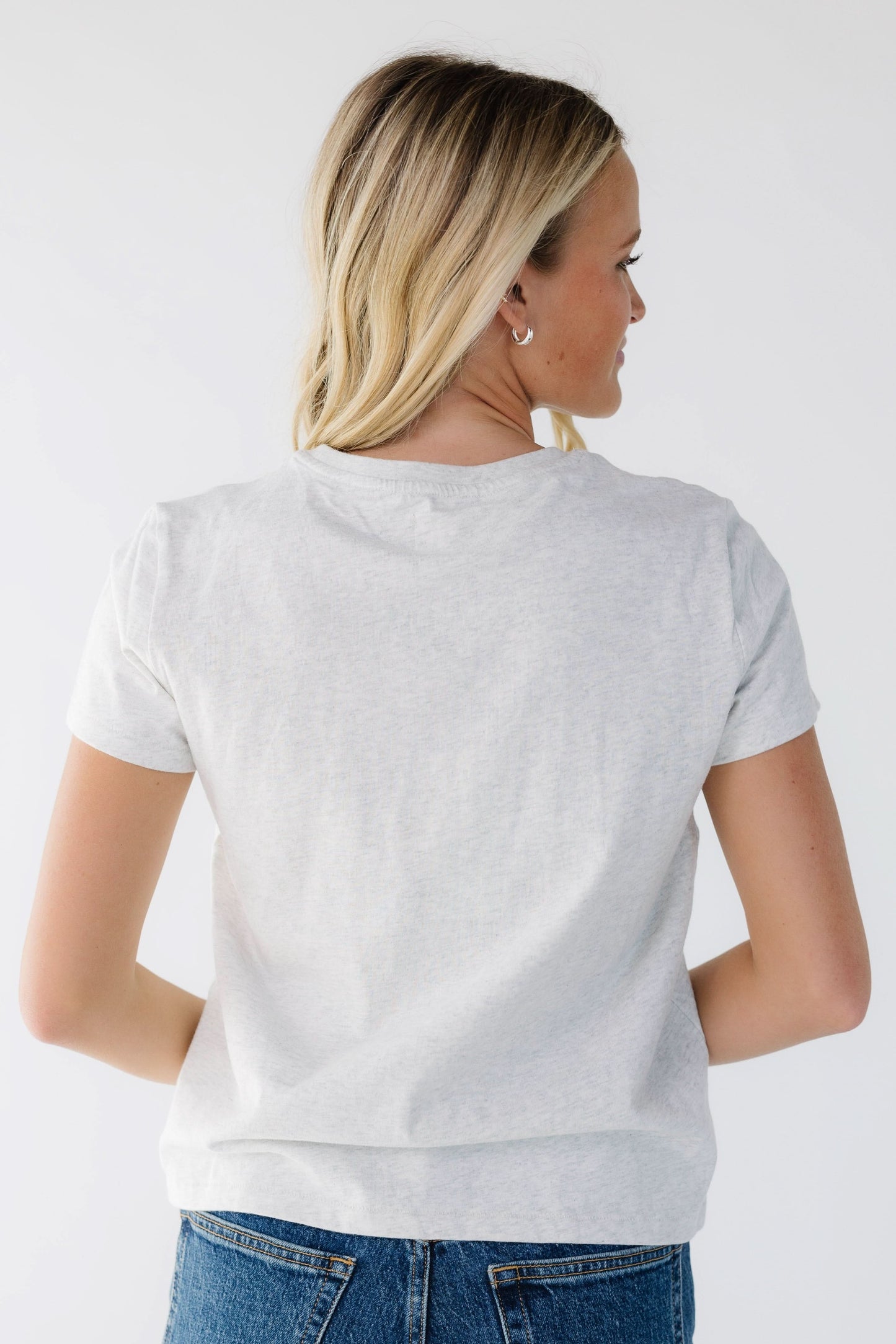 Back view of a woman wearing a short sleeve light grey t-shirt.