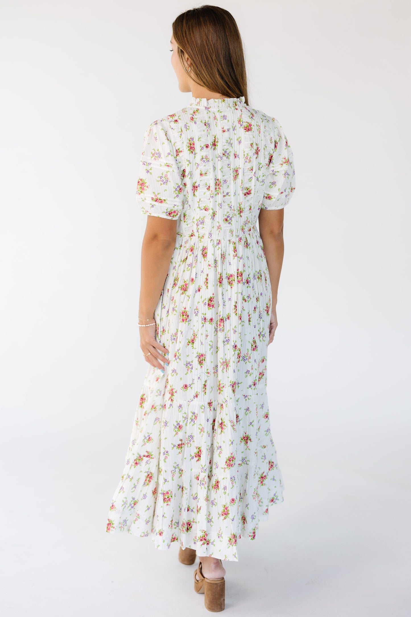 Back view of a woman wearing a cream floral midi-maxi dress with shrot sleeves.