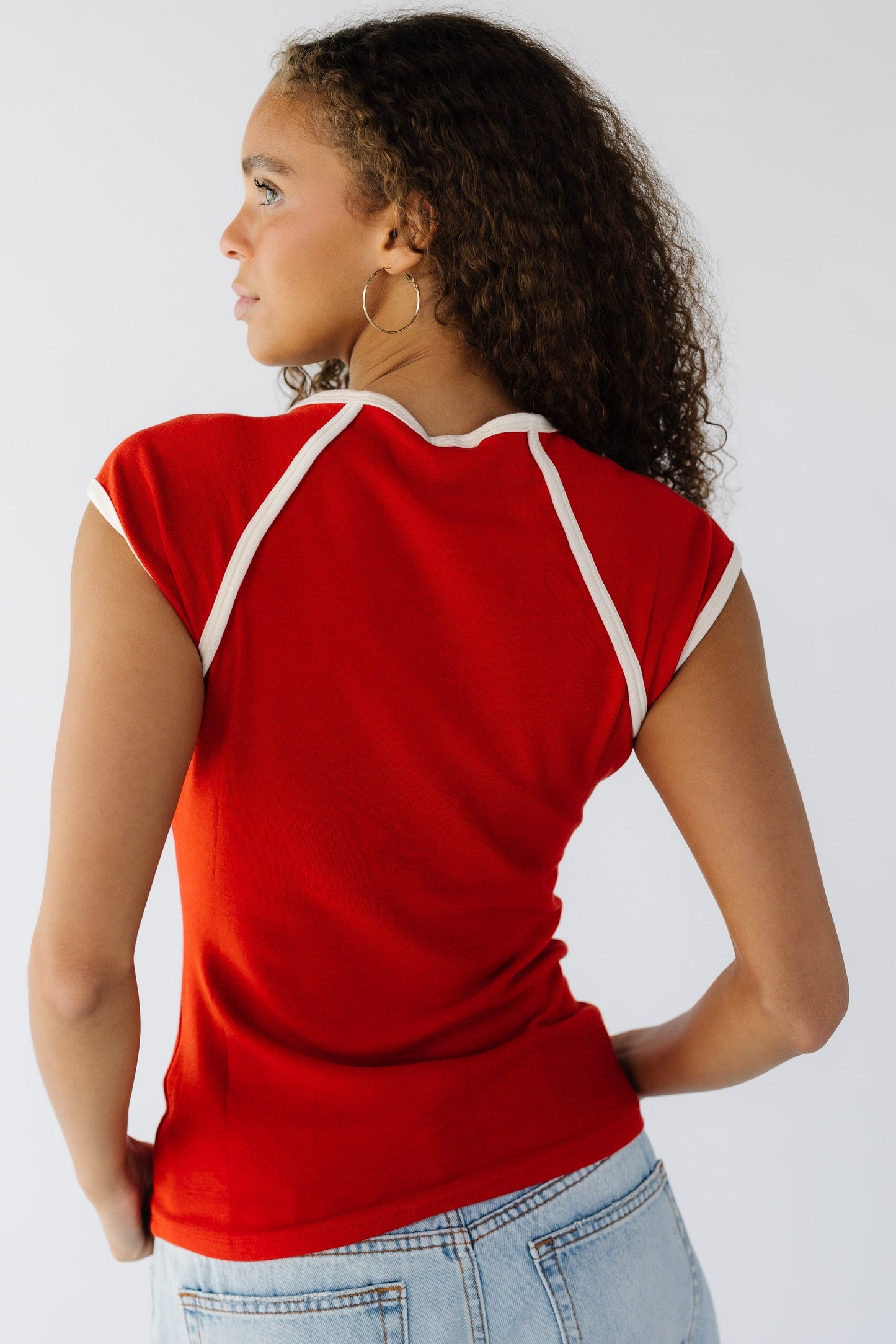 Back view of a teen girl wearing a red rib knit top with cream trim details.