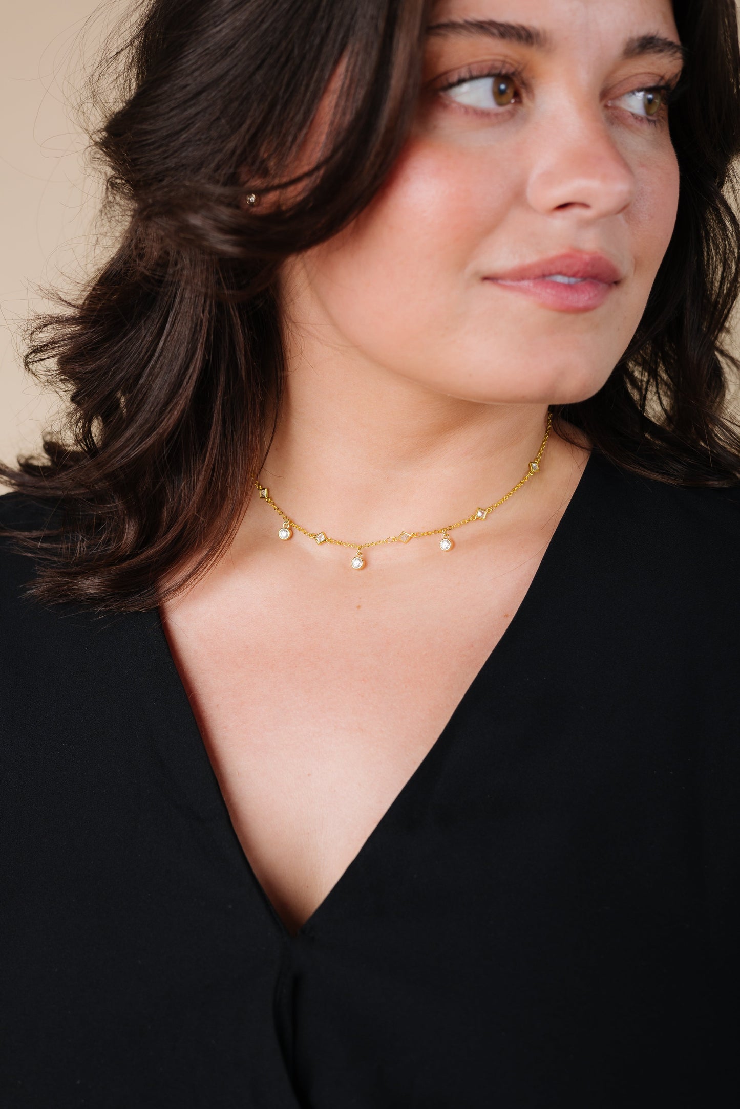 Woman wearing a gold necklace with cubic zirconia charms