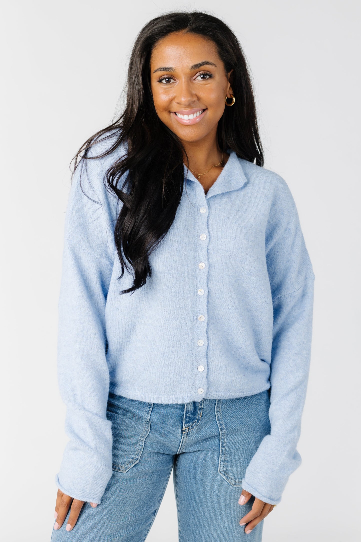 A woman wearing a light blue cardigan with white buttons