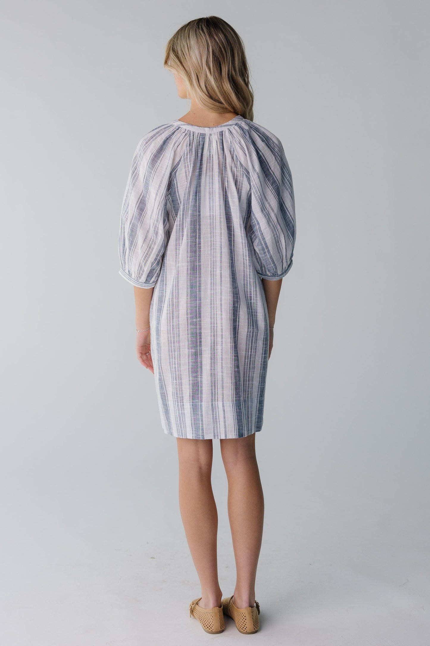 Back view of white and blue stripe knee length dress with three quarters length sleeves