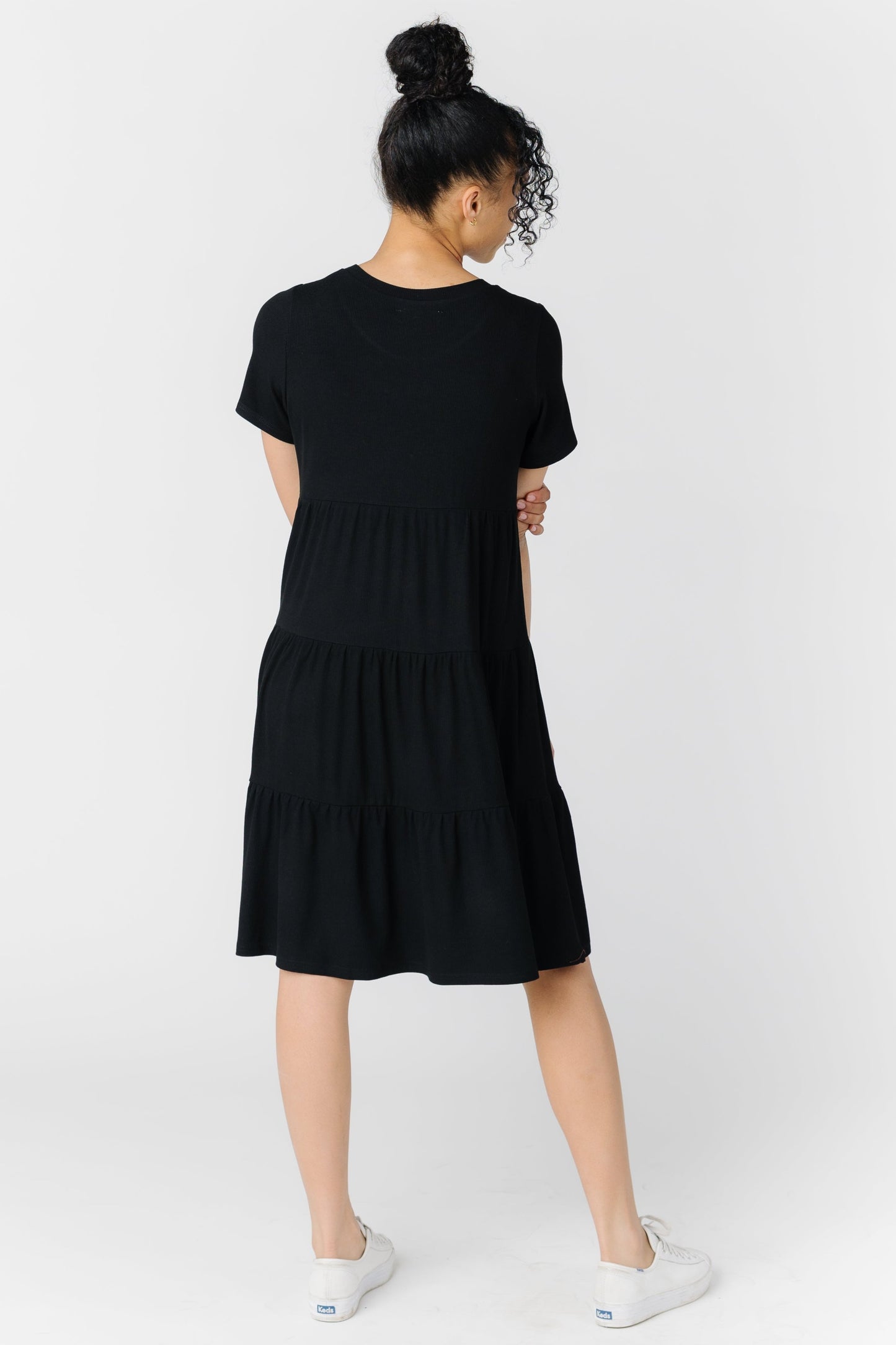Back view of a woman wearing a black tiered dress with short sleeves