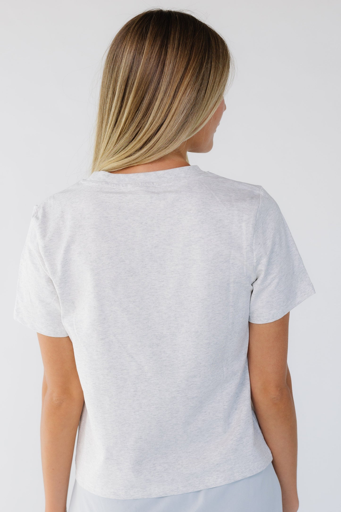 Back view of a woman wearing a heather grey short sleeve tee.