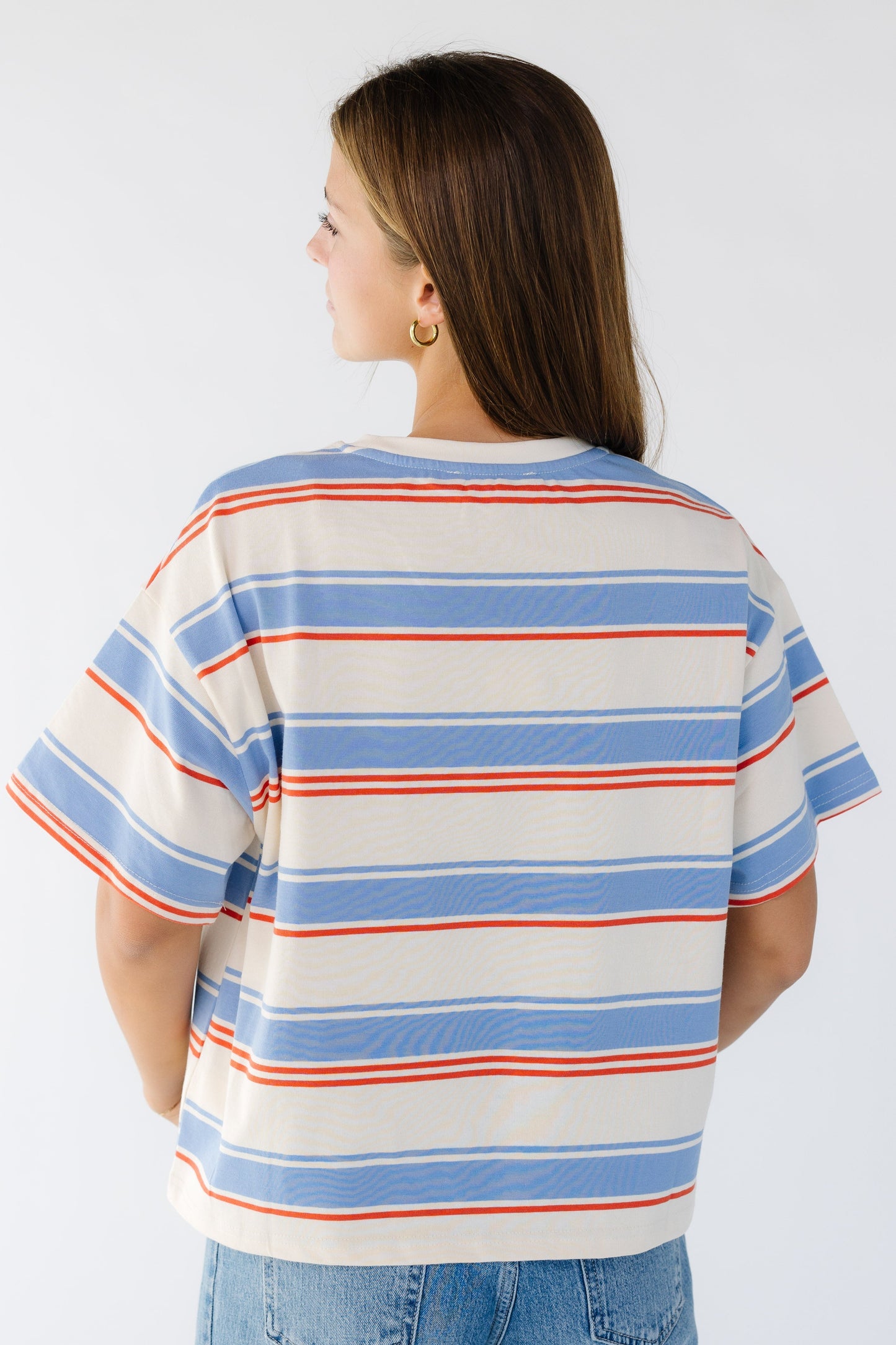Back view of a woman wearing a loose fitting stripe short sleeve tee.