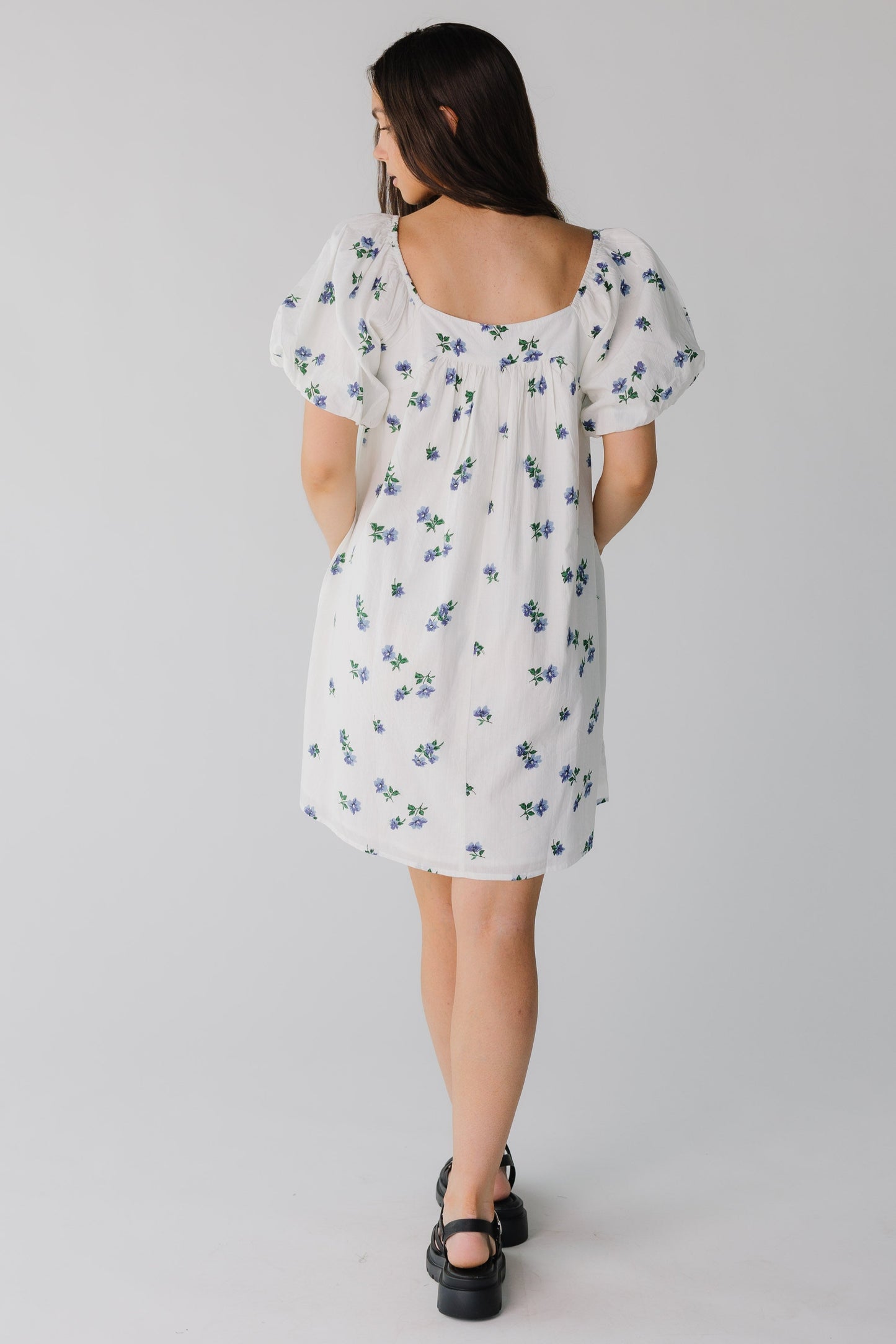 Back view of white short dress with blue floral print and square neckline