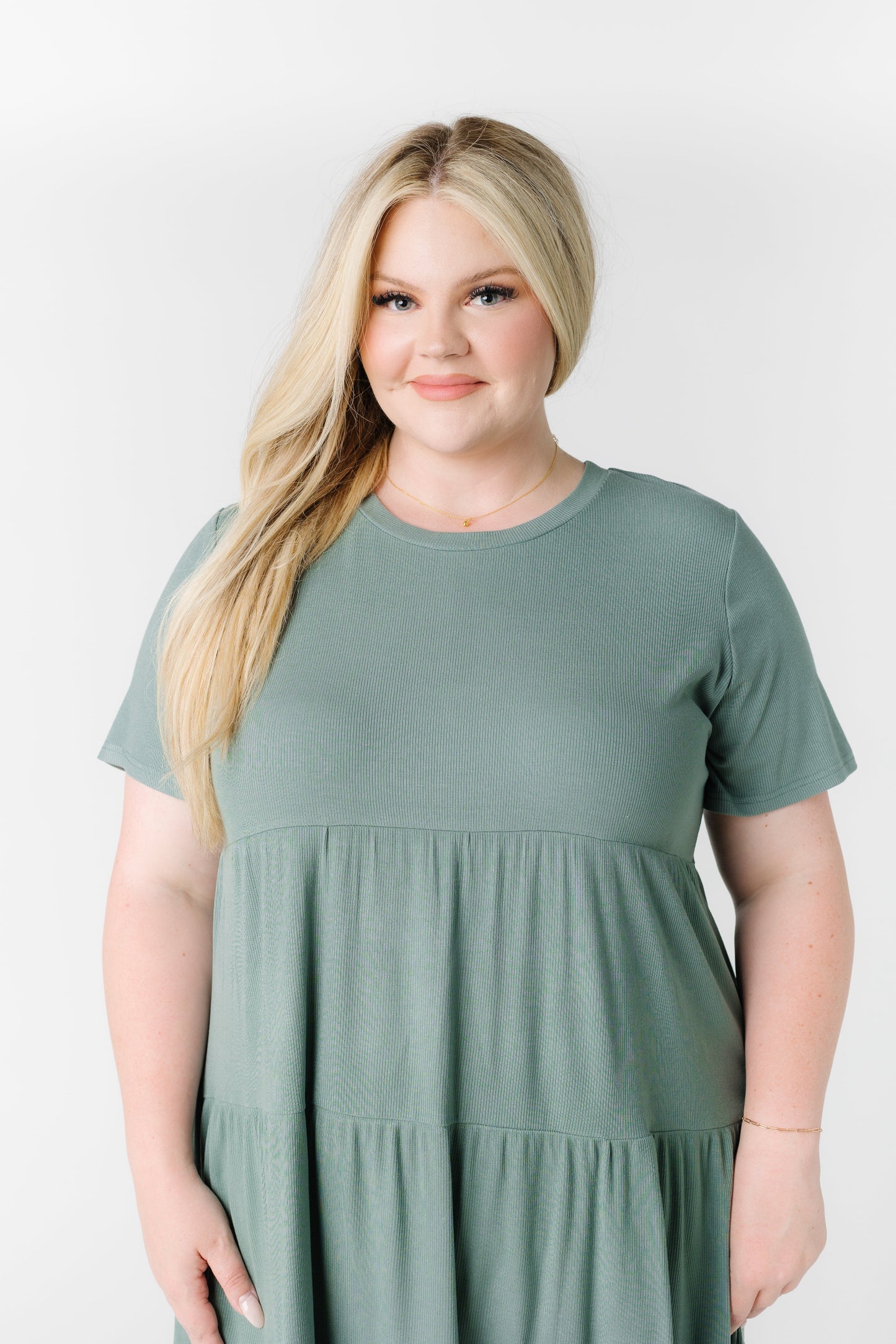 A woman wearing a green tiered dress in plus