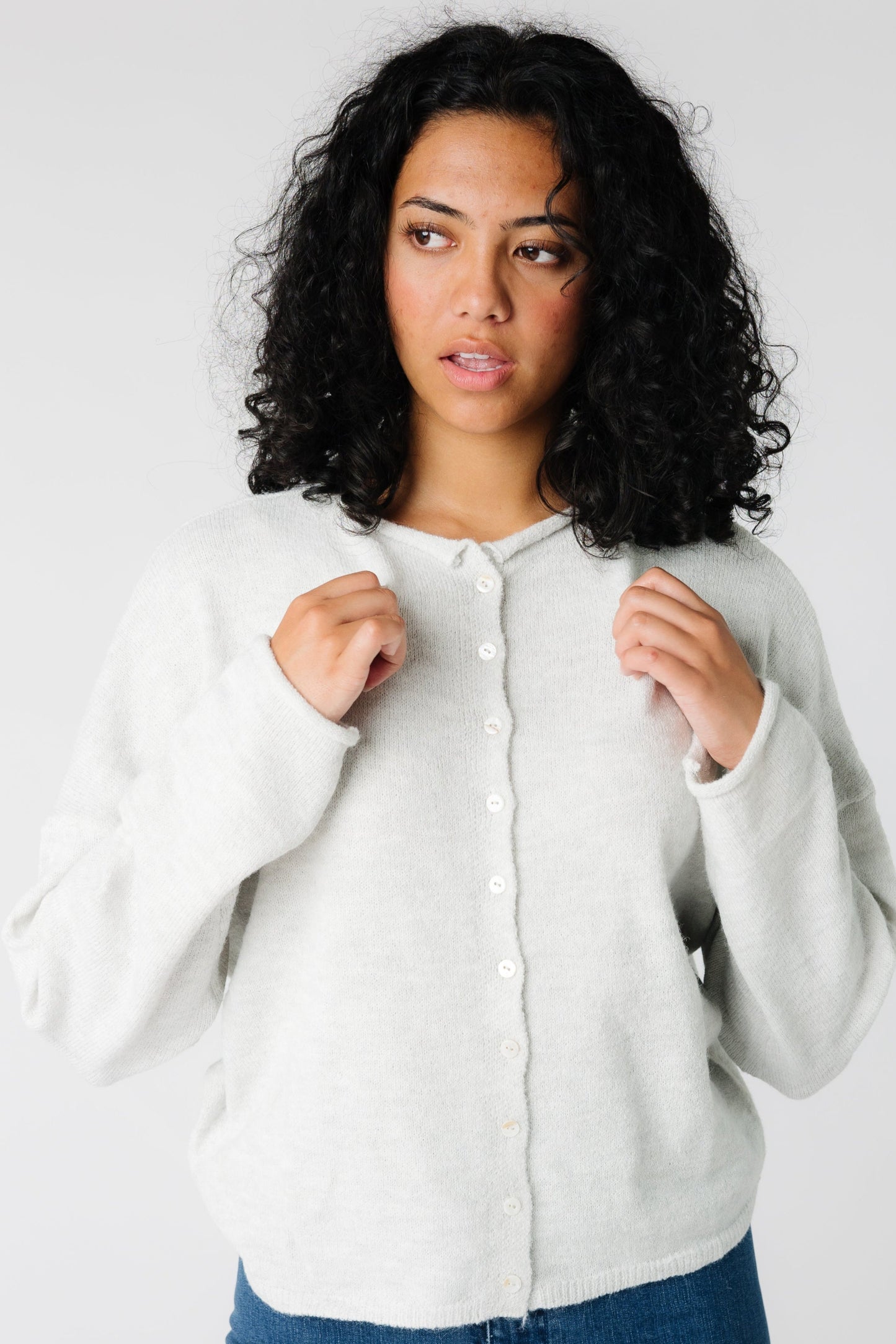 A woman wearing a light grey button down cardigan