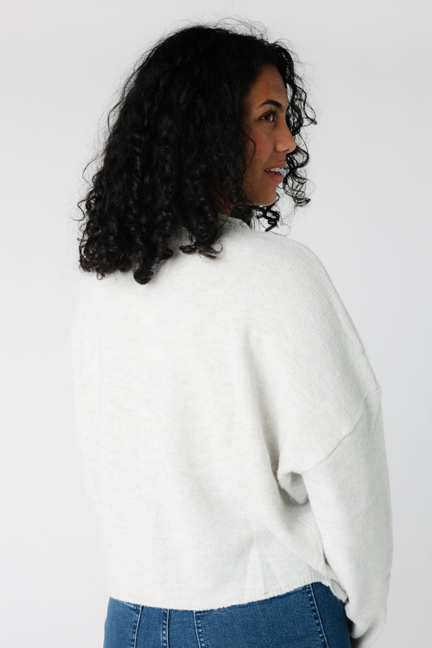 A back view of a woman wearing a light grey sweater with long sleeves