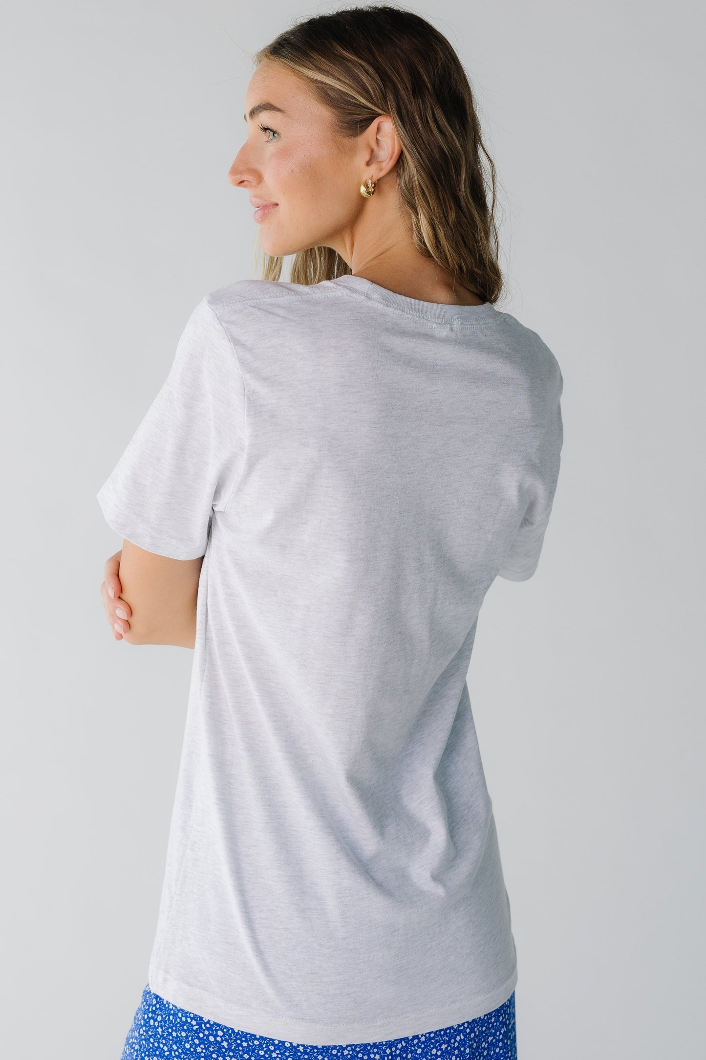 Back view of a woman wearing a light grey short sleeve tee.