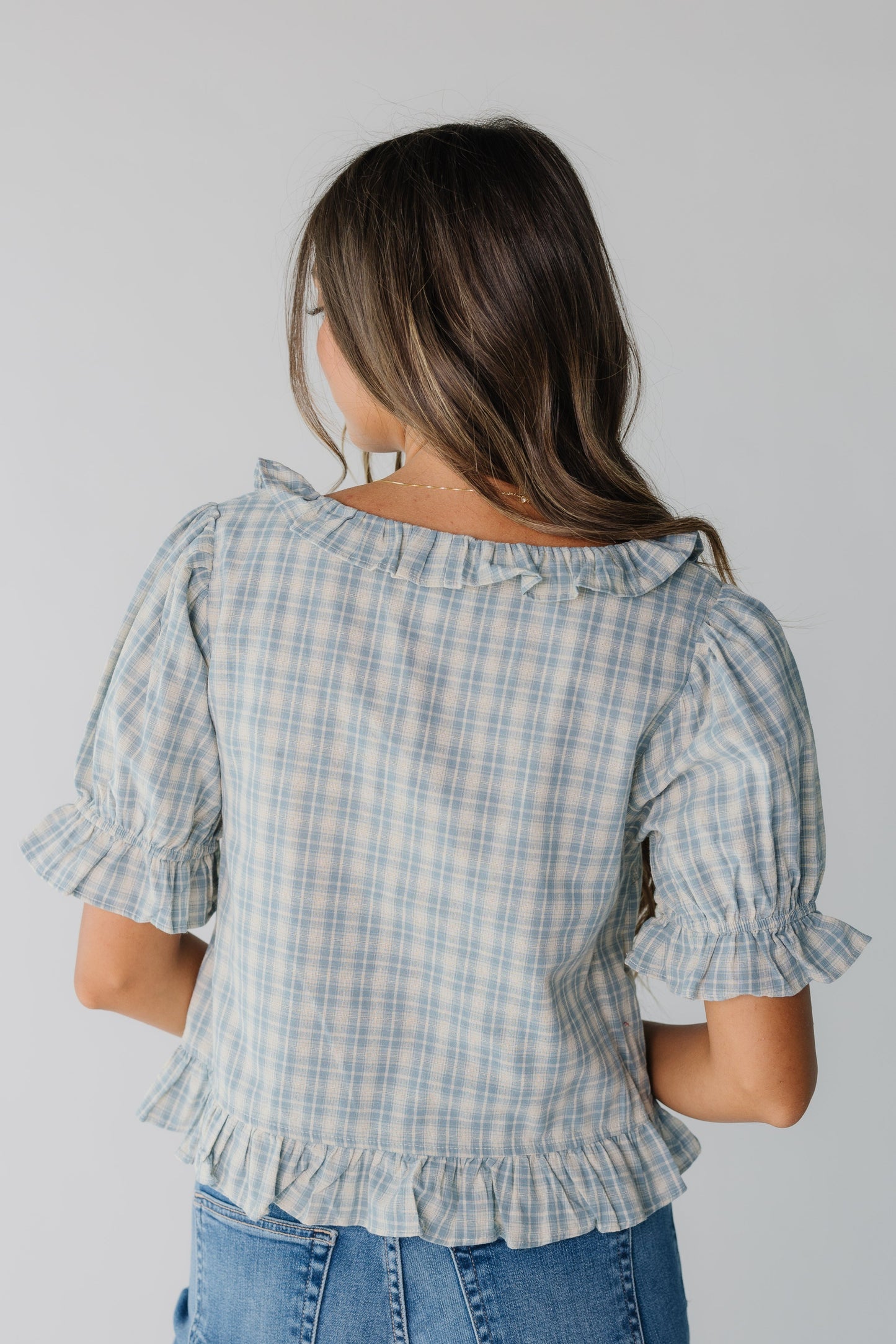 Back view of women's blue plaid top with ruffles