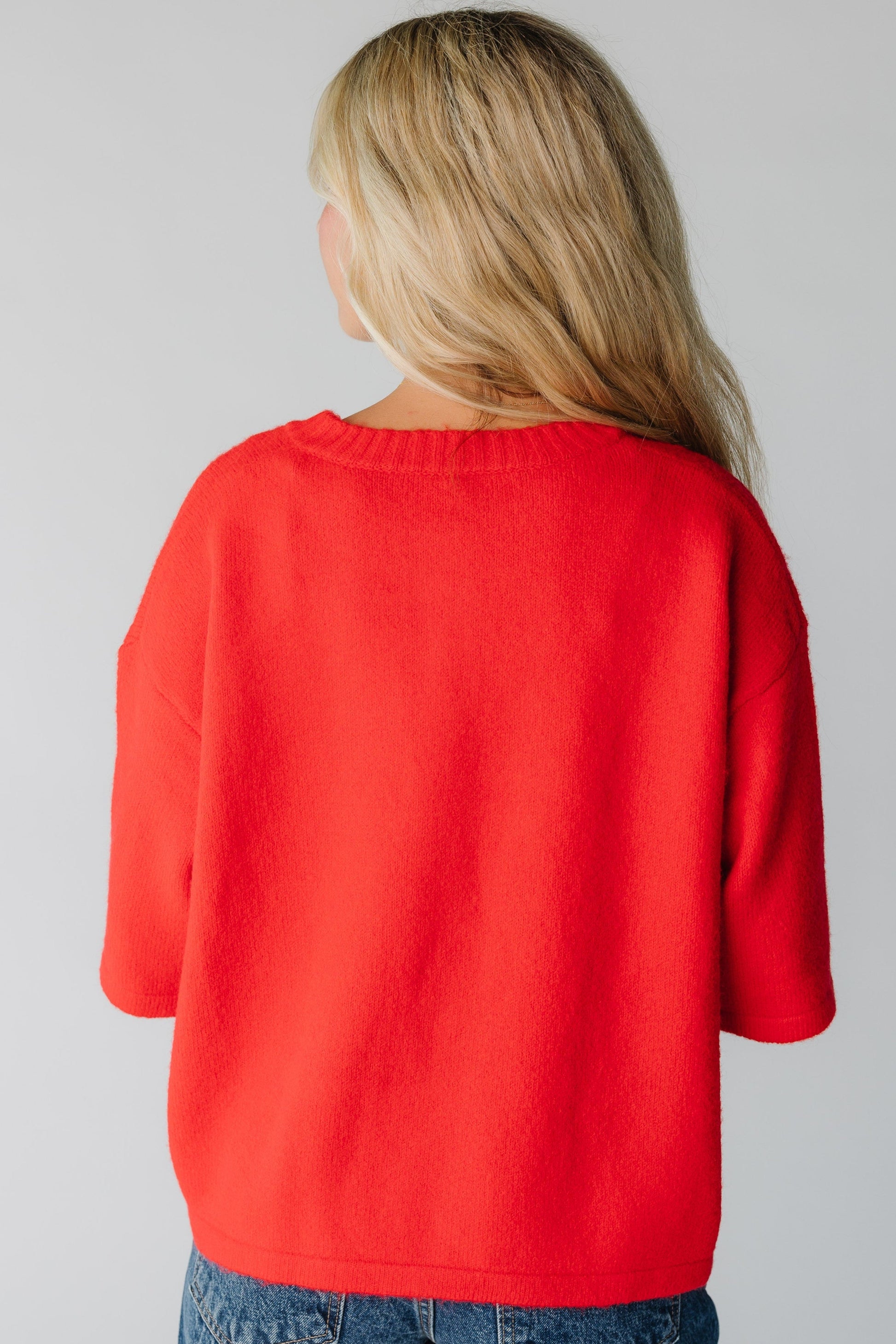 Back view of woman wearing a red sweater with half length sleeves