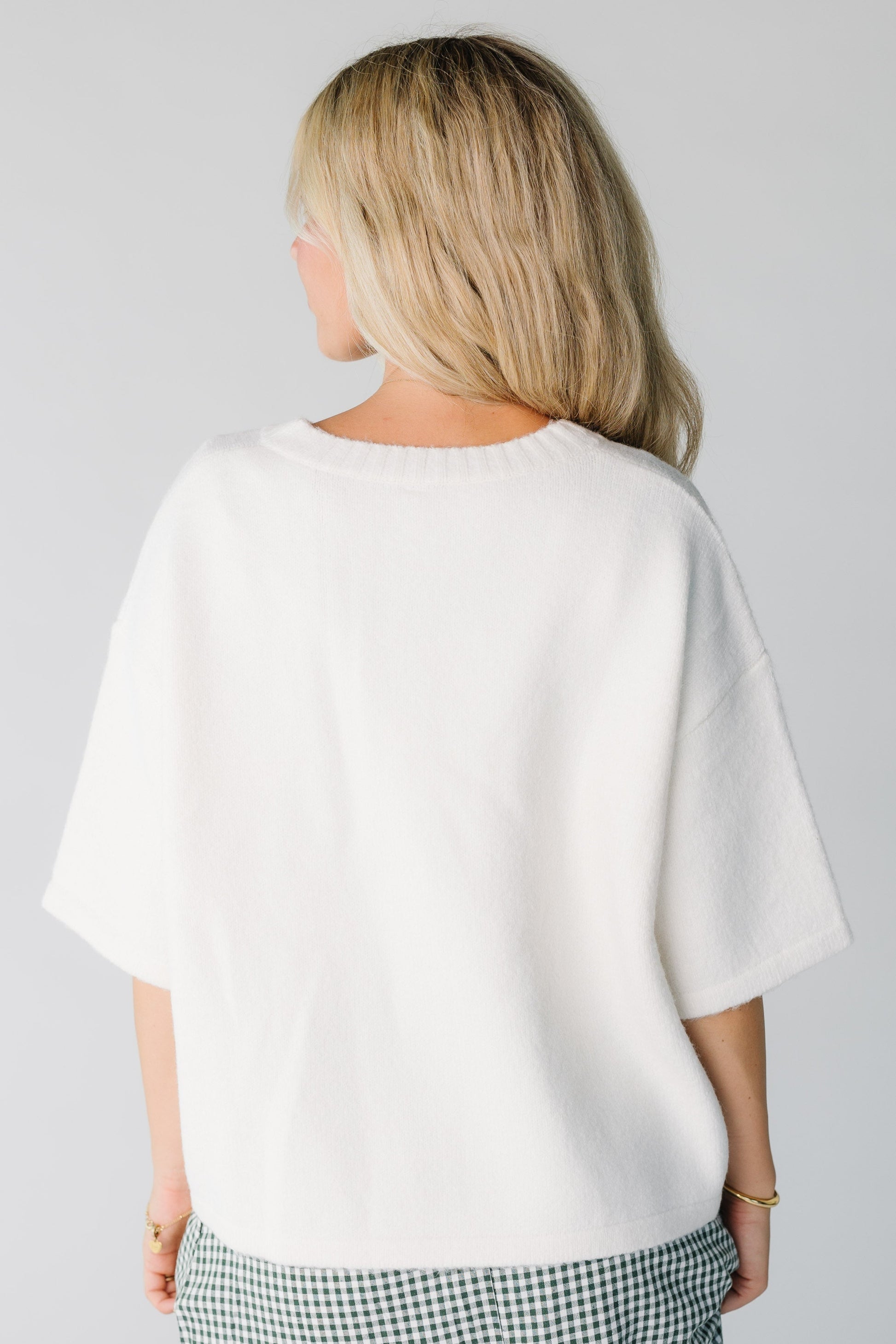Woman wearing an off white loose fitting cardigan with half length sleeves
