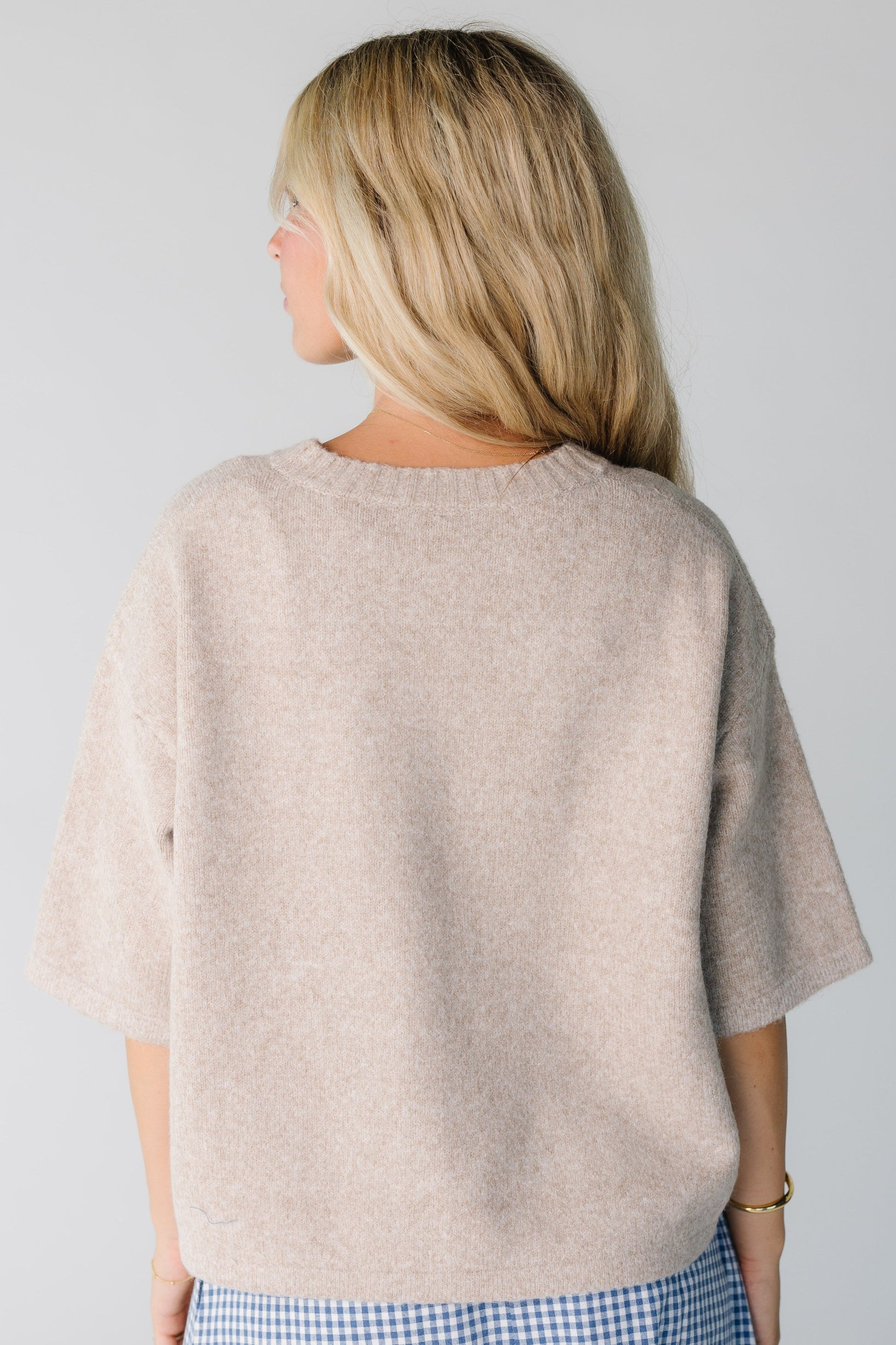 Back view of women wearing a loose fitting mocha sweater with half length sleeves