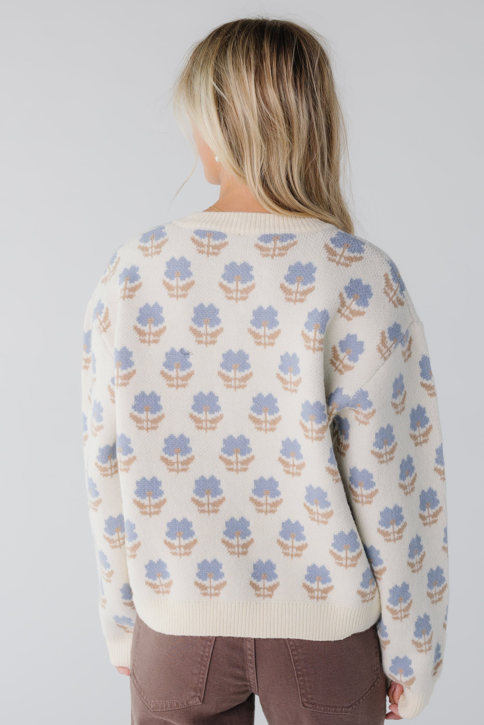 Back view of woman wearing a blue and cream floral cardigan with long sleeves