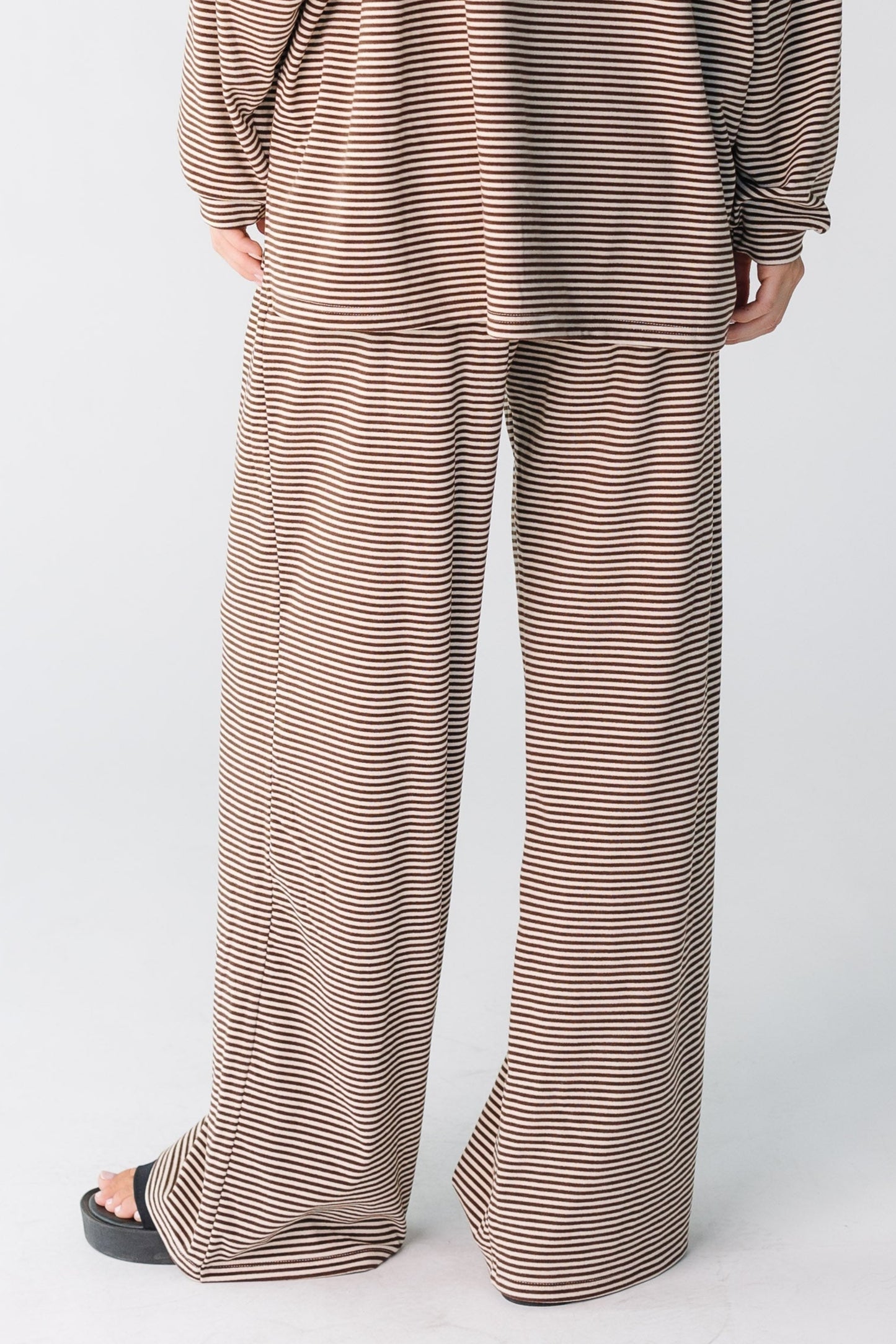 Back view of a women wearing a brown stripe pant cut with long sleeves