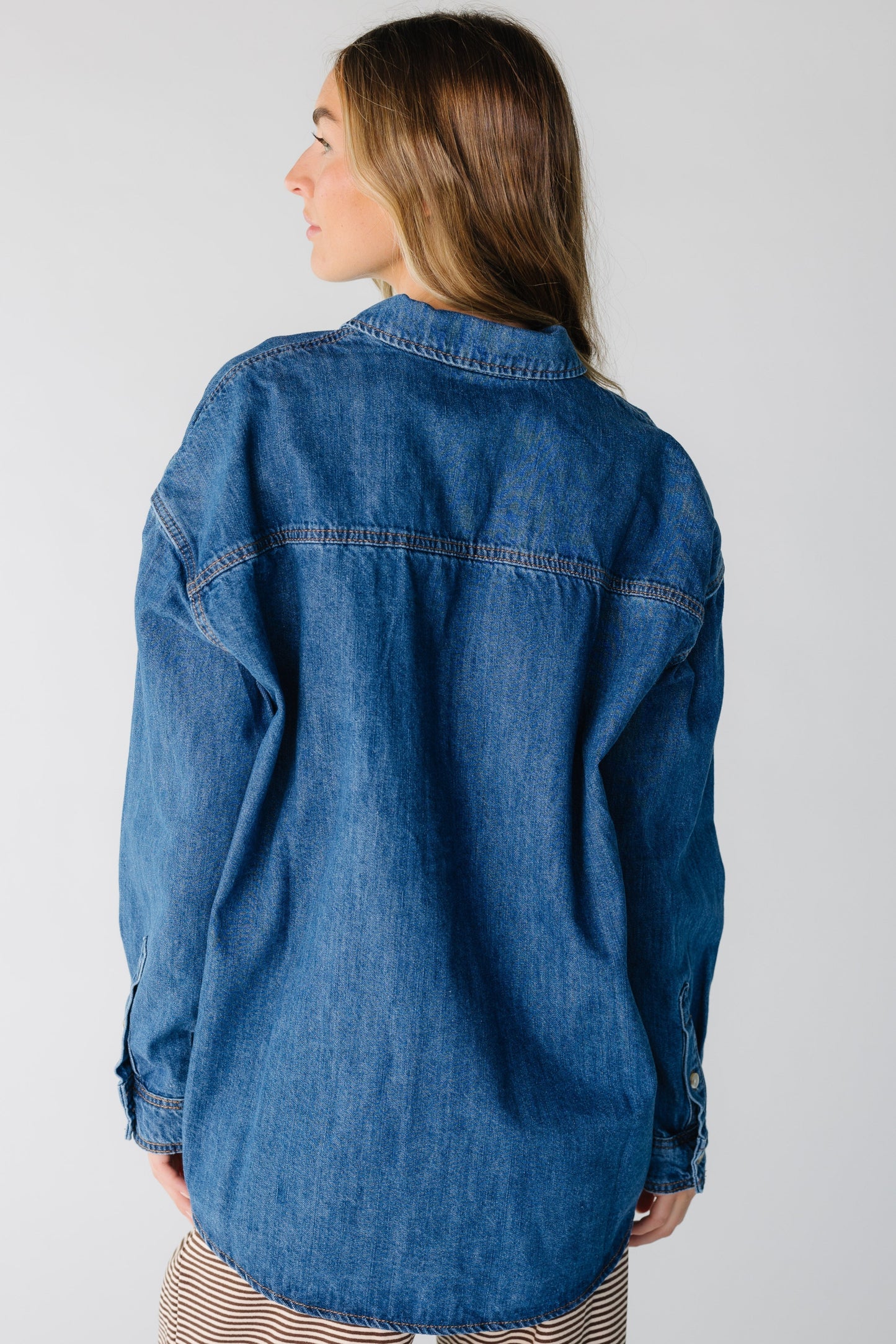 Back view of a woman wearing a loose denim shirt