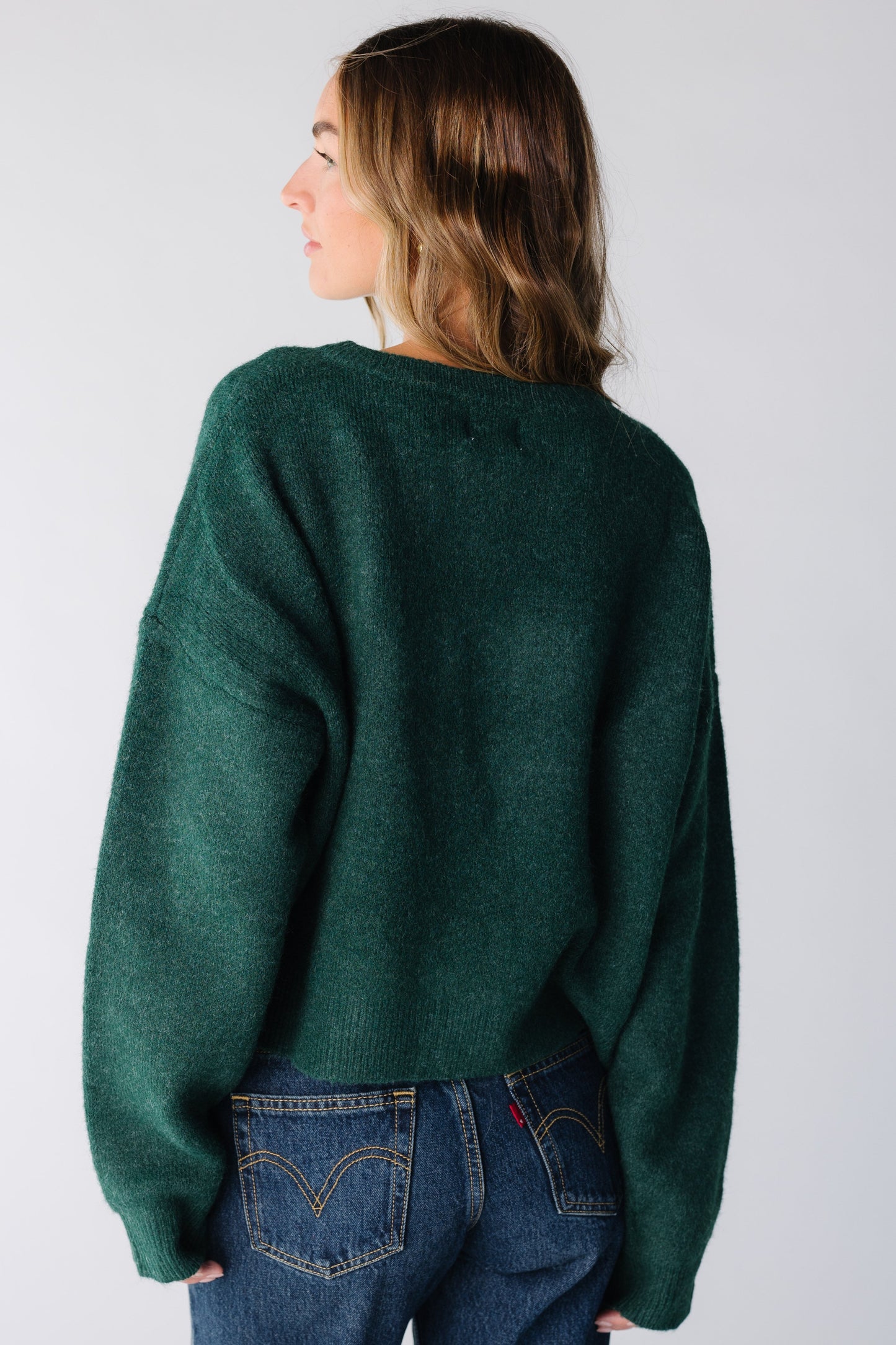 Back view of a woman wearing a dark green cardigan with long sleeves