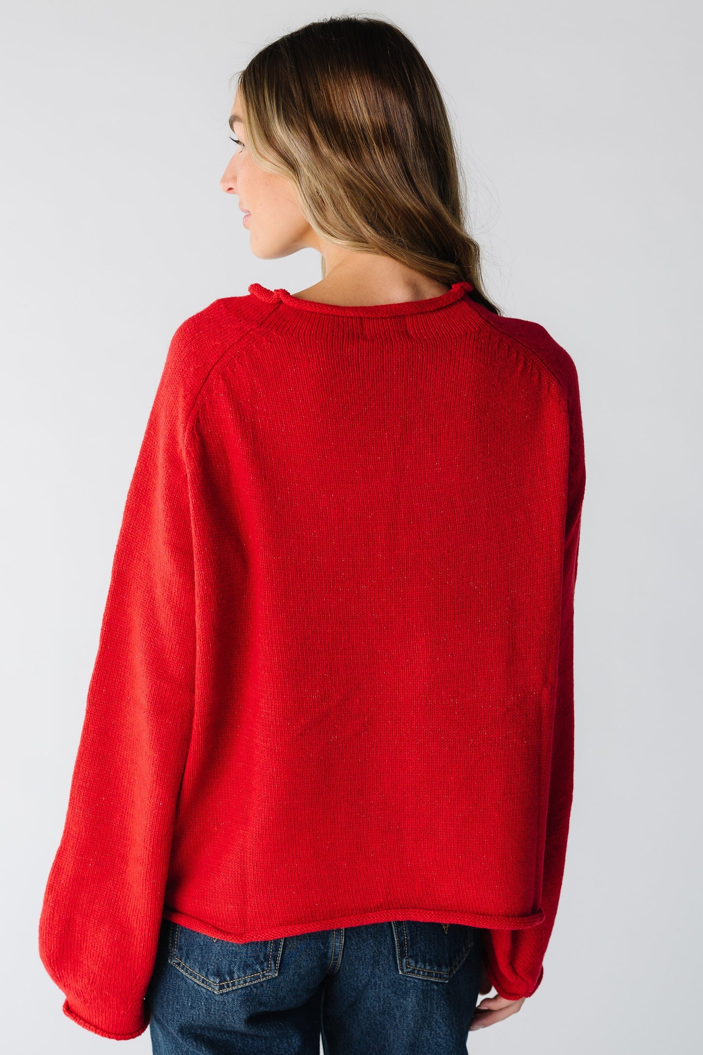 Back view of woman wearing a loose fitting red sweater with long sleeves