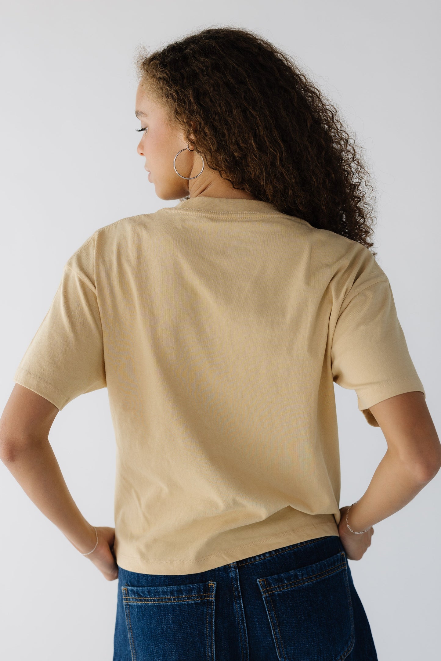 Back view of a teenage girl wearing a yellow short sleeve tee.