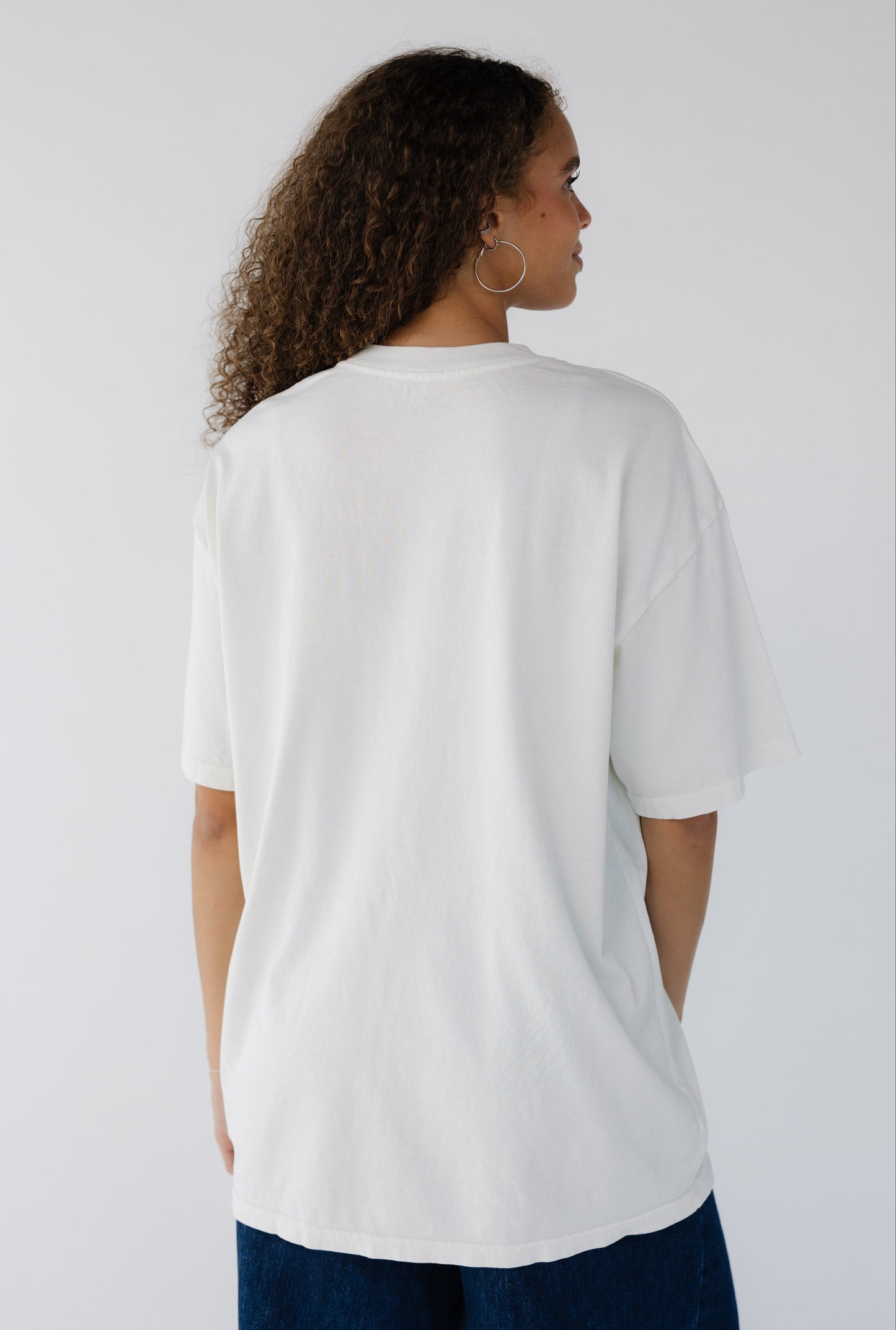 Teenage girls wearing a light cream oversized tee with short sleeves.