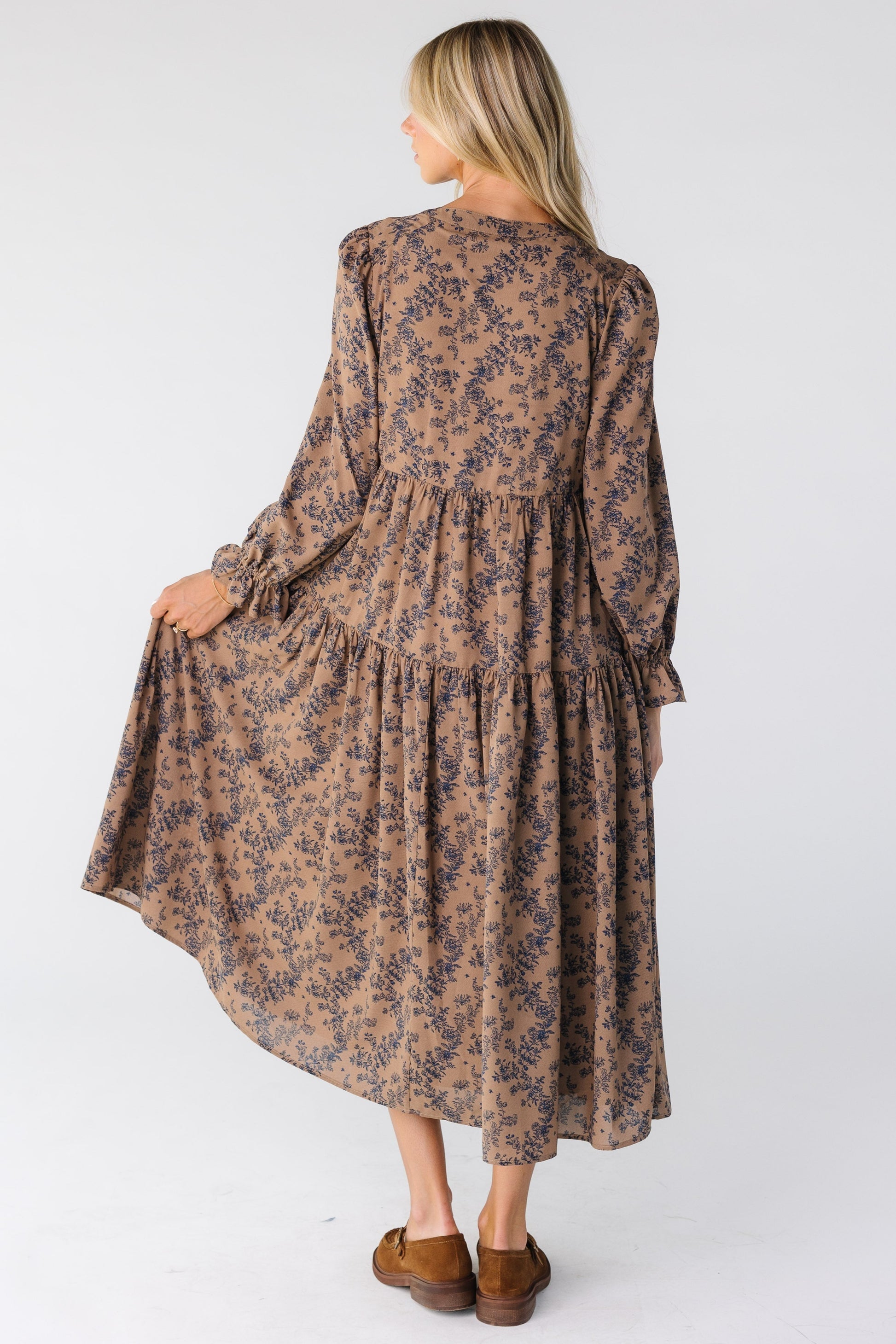 Back view of a woman wearing a loose fitting tiered dress with navy floral print