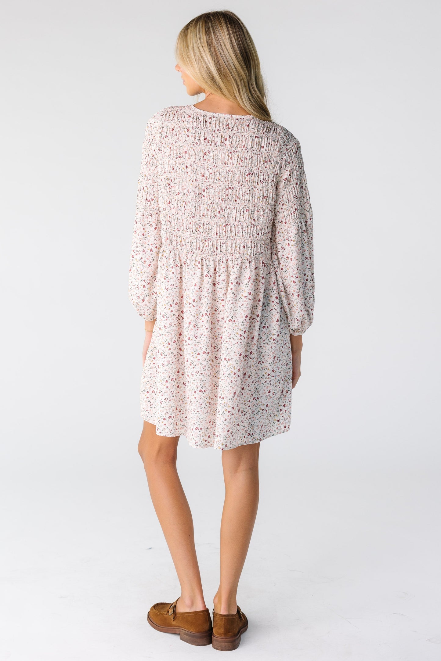 Back view of a woman wearing a cream floral print short dress