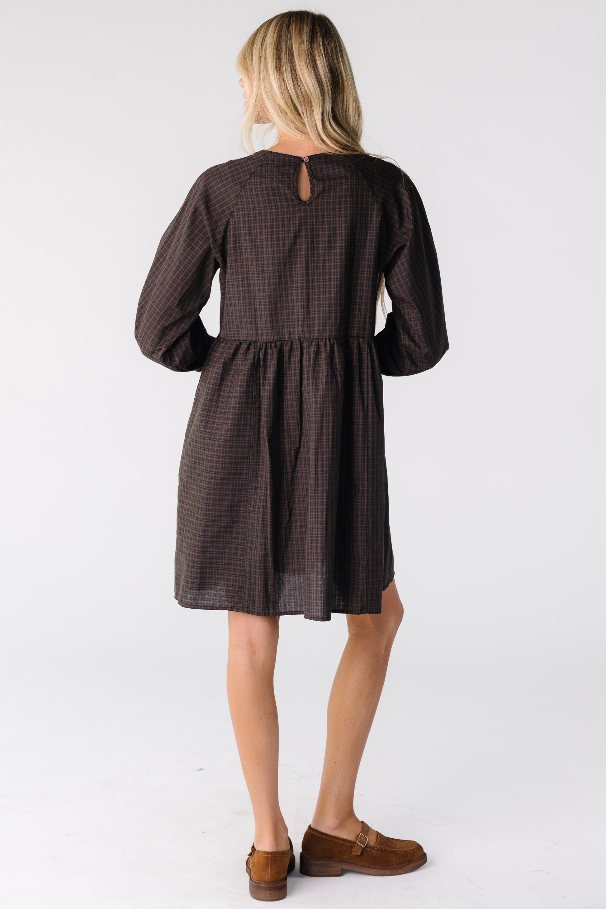 Back view of a woman wearing a brown plaid dress with long sleeves