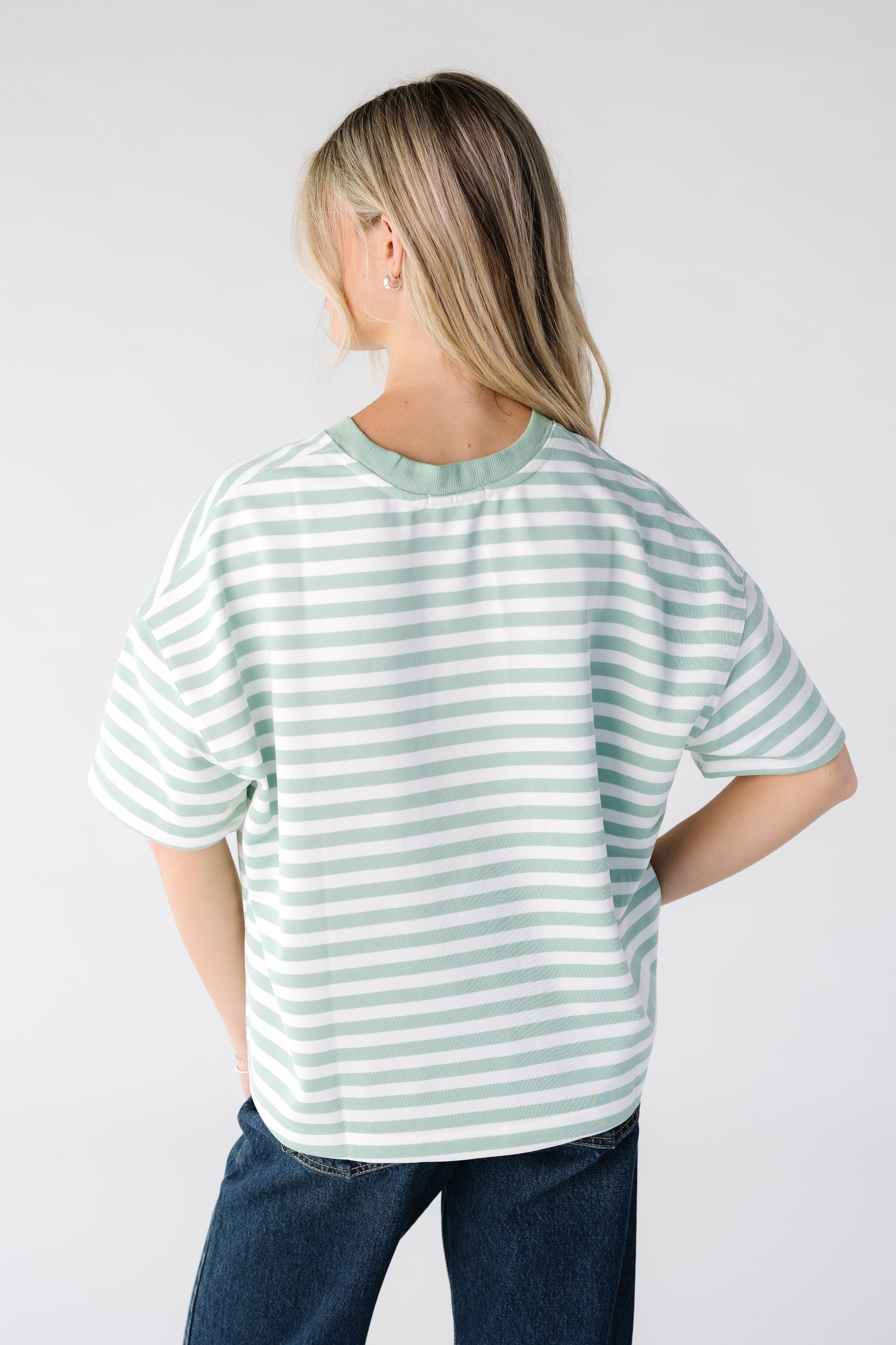 Back view of a woman wearing a mint and white stripe boxy tee