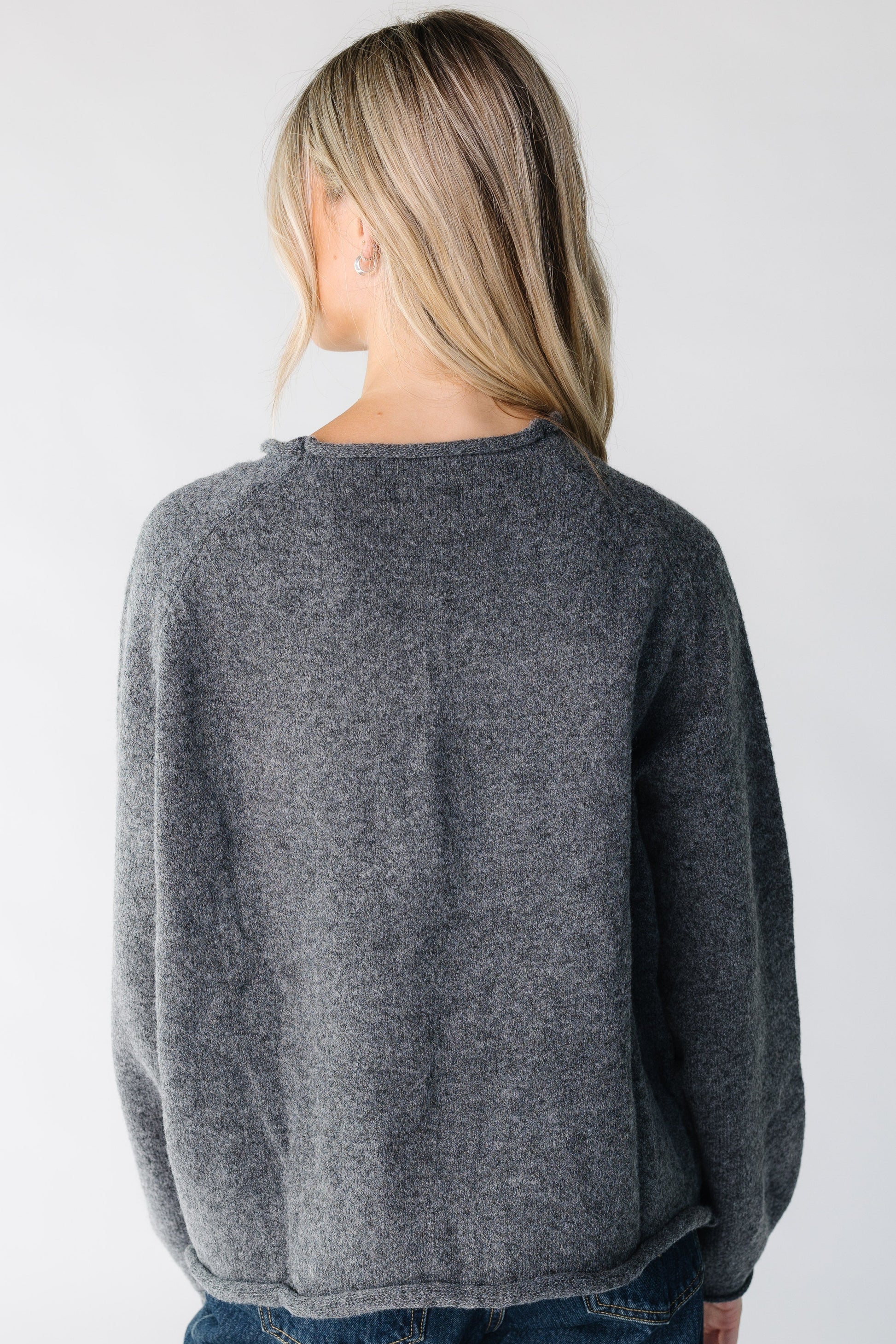 Woman wearing a charcoal long sleeve sweater.