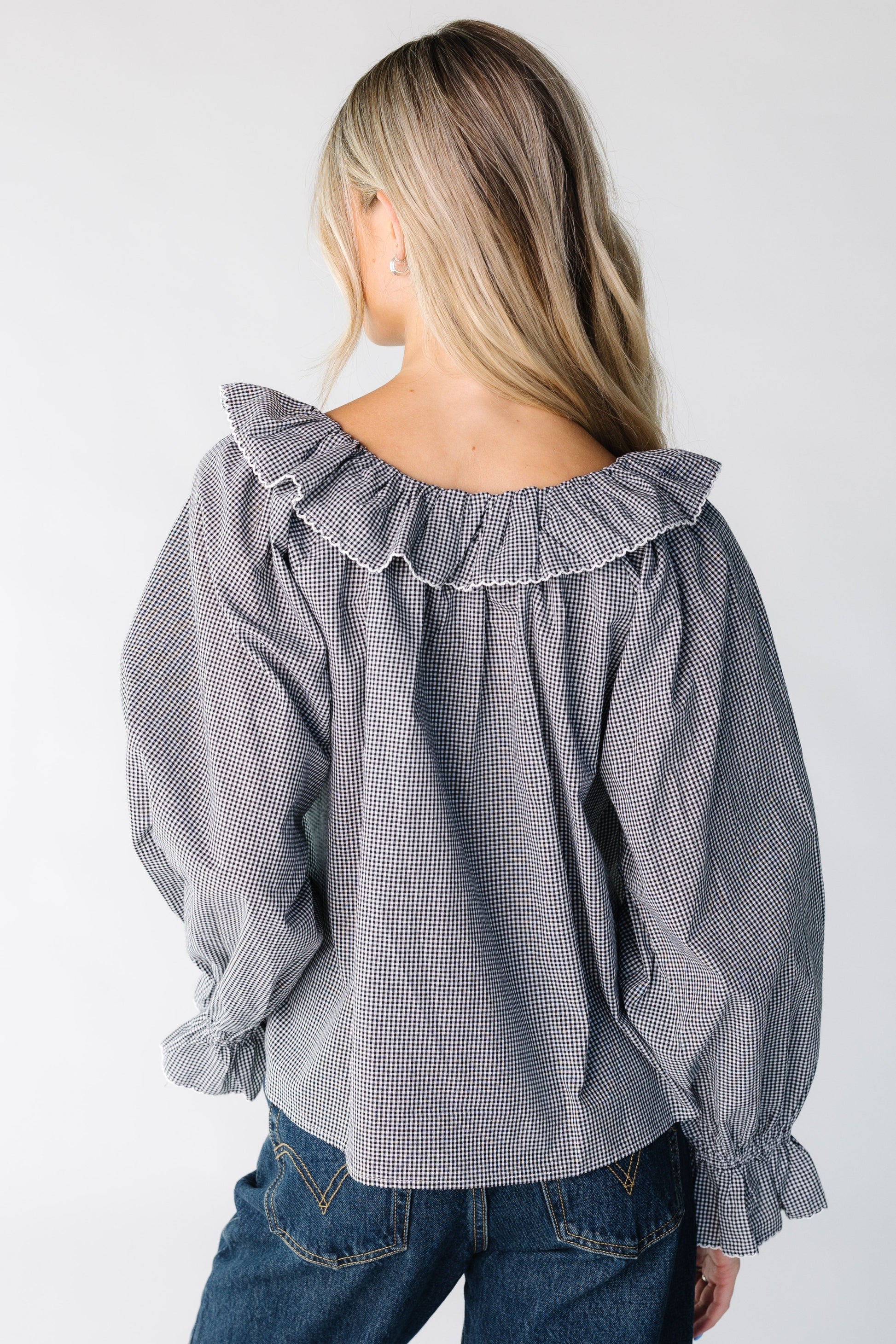 Back view of a woman wearing a black and white gingham top