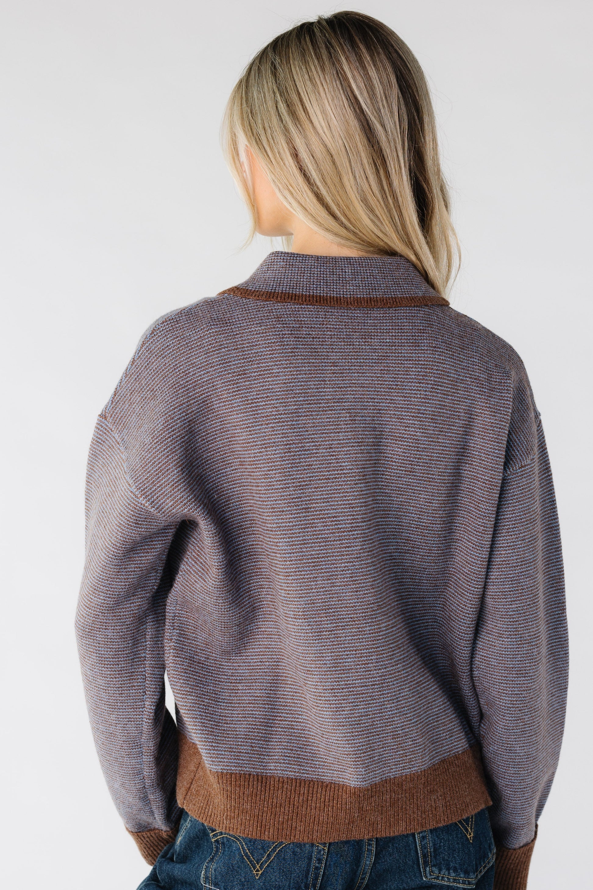 Back view of a woman wearing a brown and blue stripe sweater with narrow stripes
