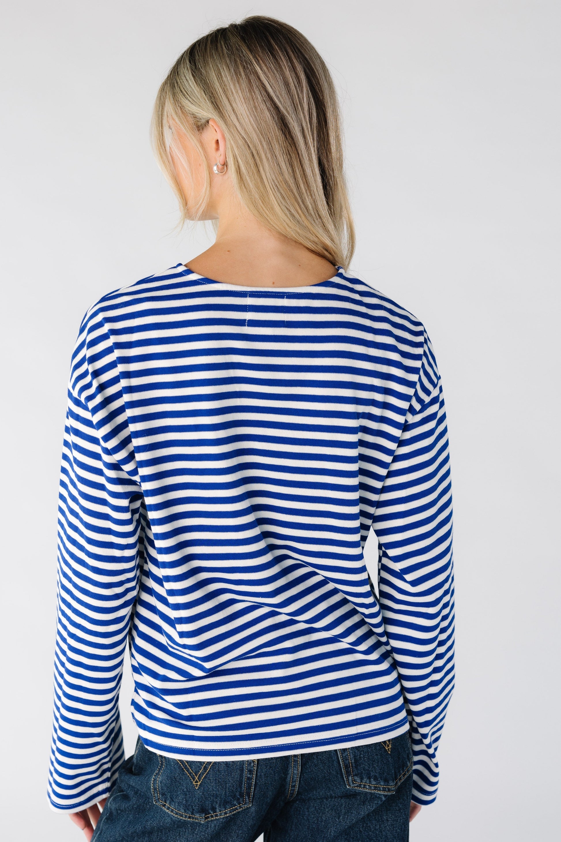Back view of a woman wearing a blue and white stripe long sleeve tee