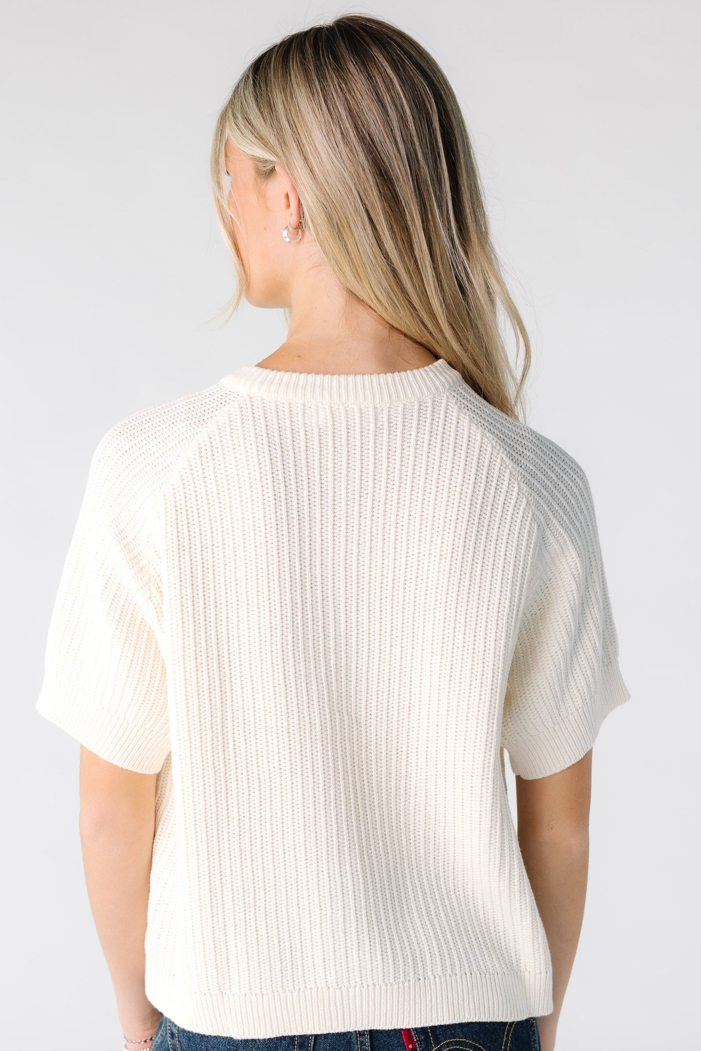 Back view of a woman wearing an ivory short sleeve sweater