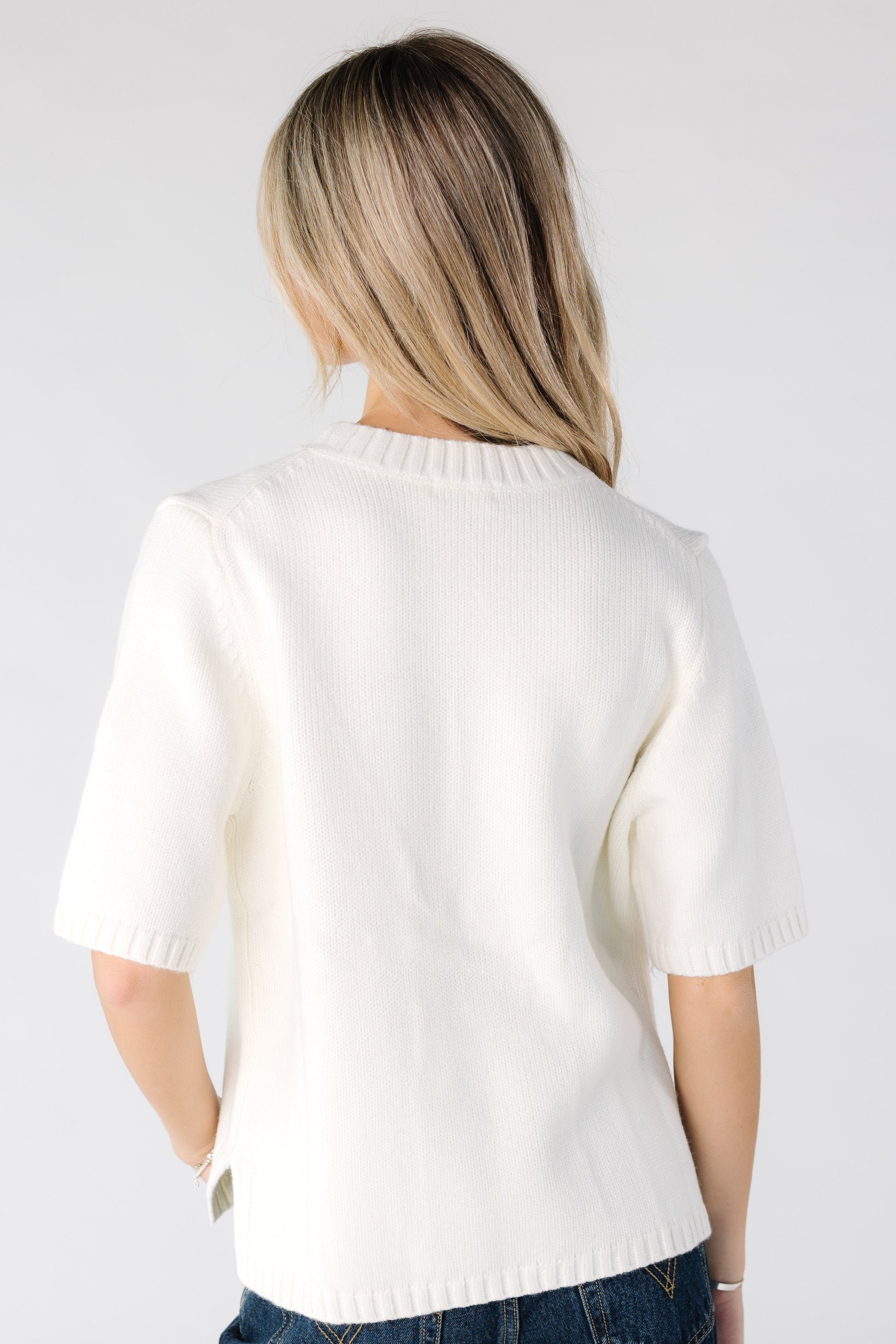 Back view of a woman wearing a cream short sleeve sweater