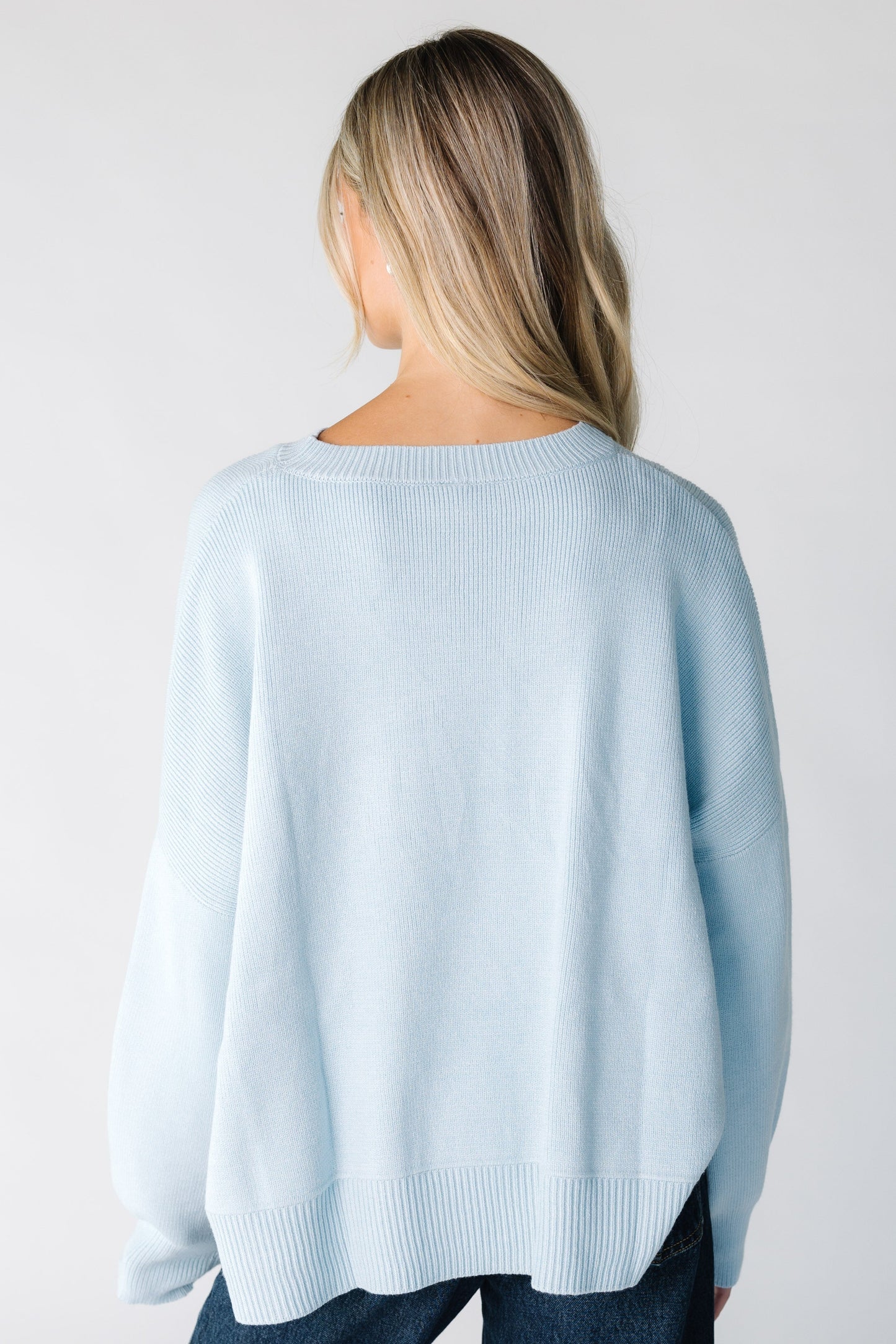 Back view of a women wearing a light blue sweater