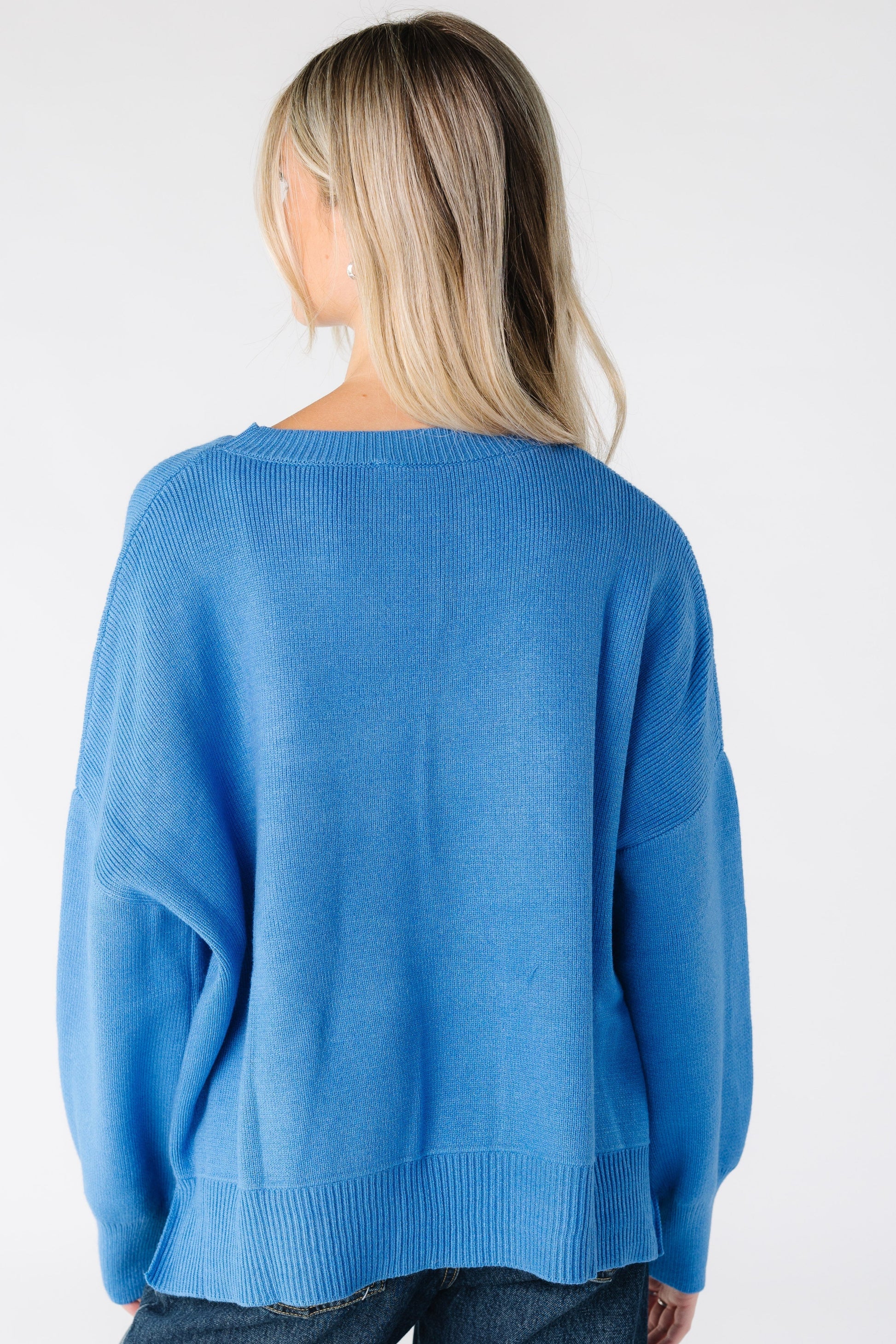 Back view of a woman wearing a blue long sleeve sweater with drop shoulders